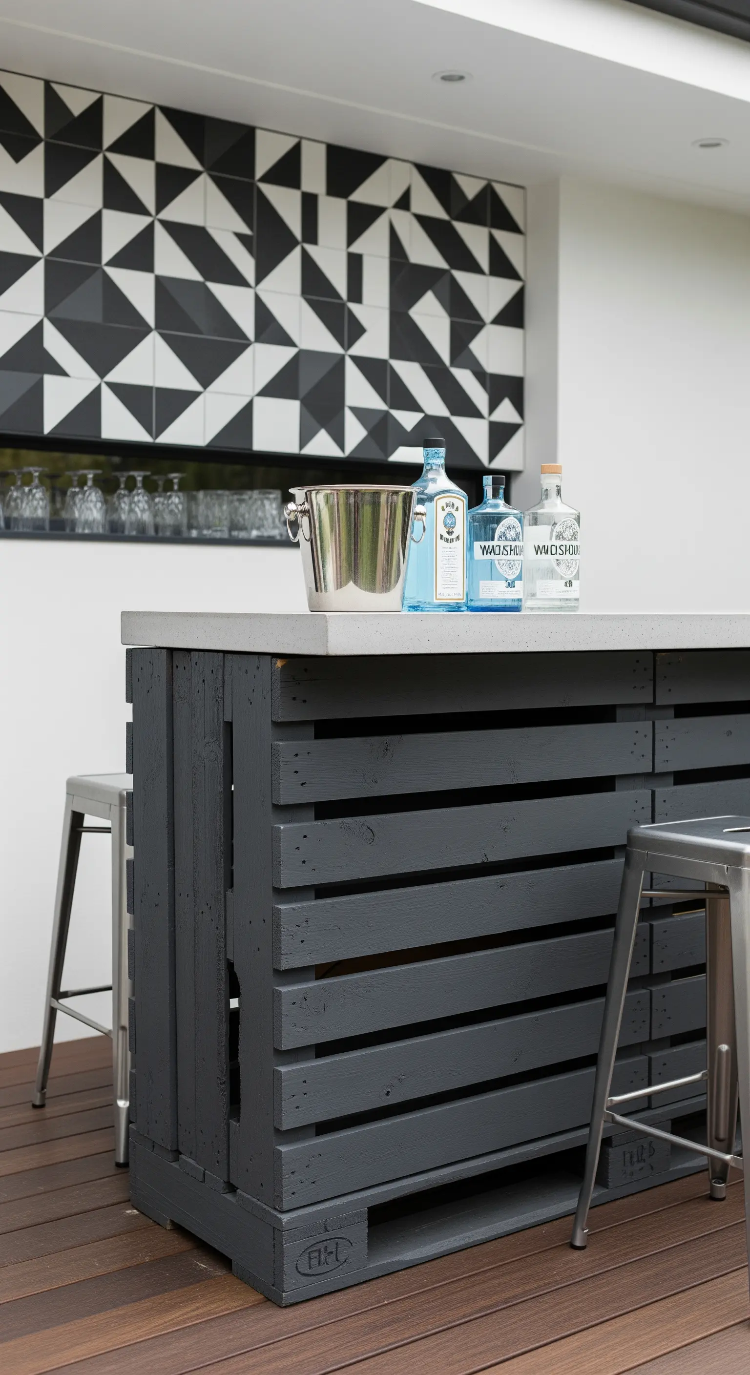 Isola bar moderna realizzata con pallet verniciati di grigio scuro e un backsplash geometrico.