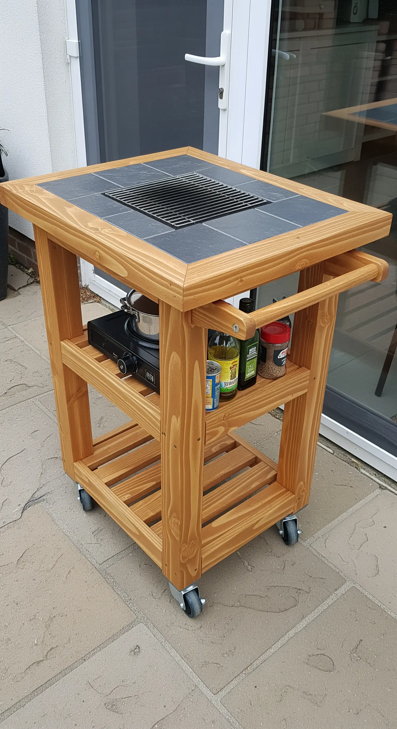 Carrello da cucina in legno con ruote, piano in ardesia e griglia integrata.