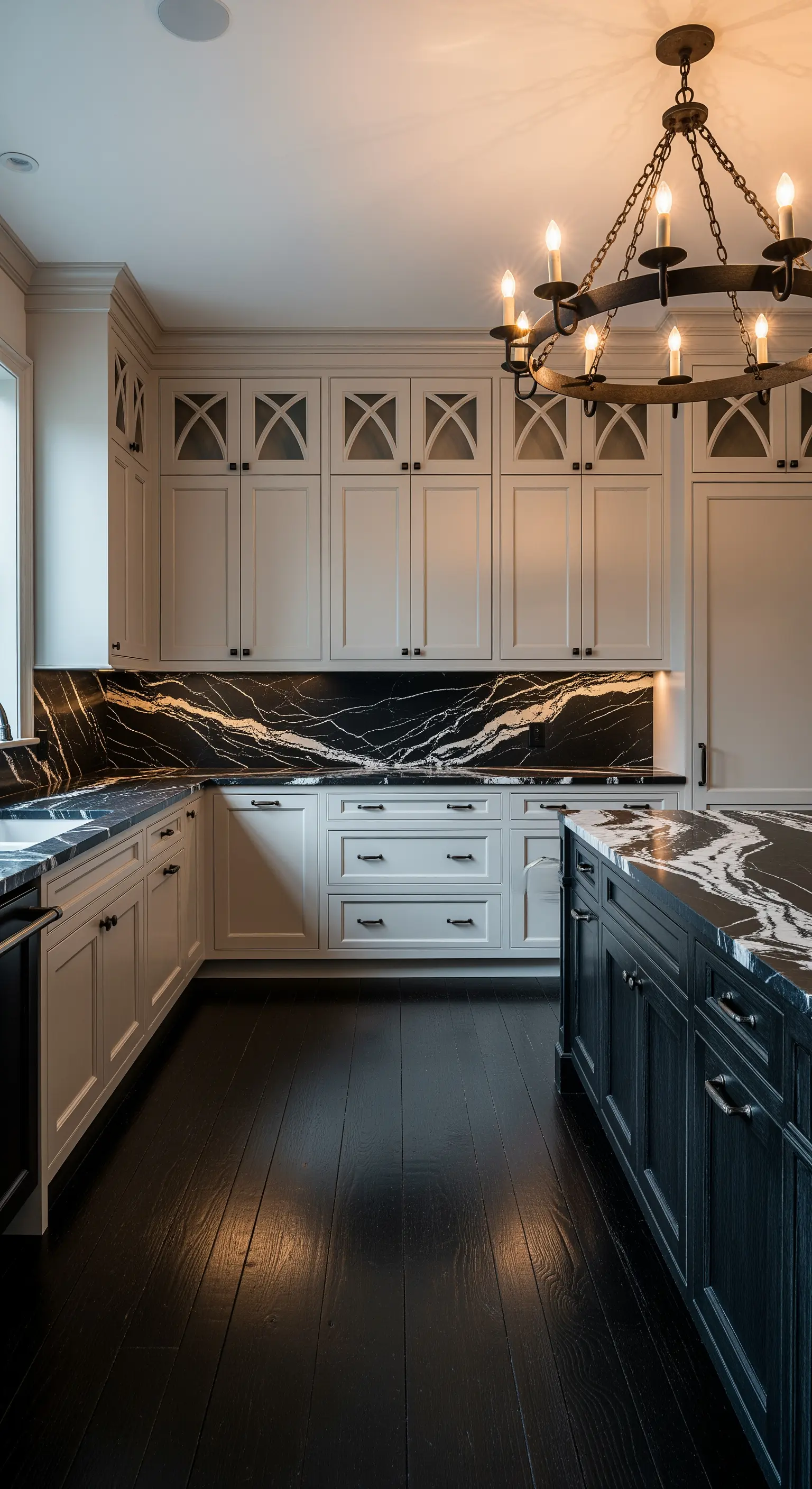 Cucina elegante con marmo nero venato, mobili bianchi e un grande lampadario in ferro battuto.