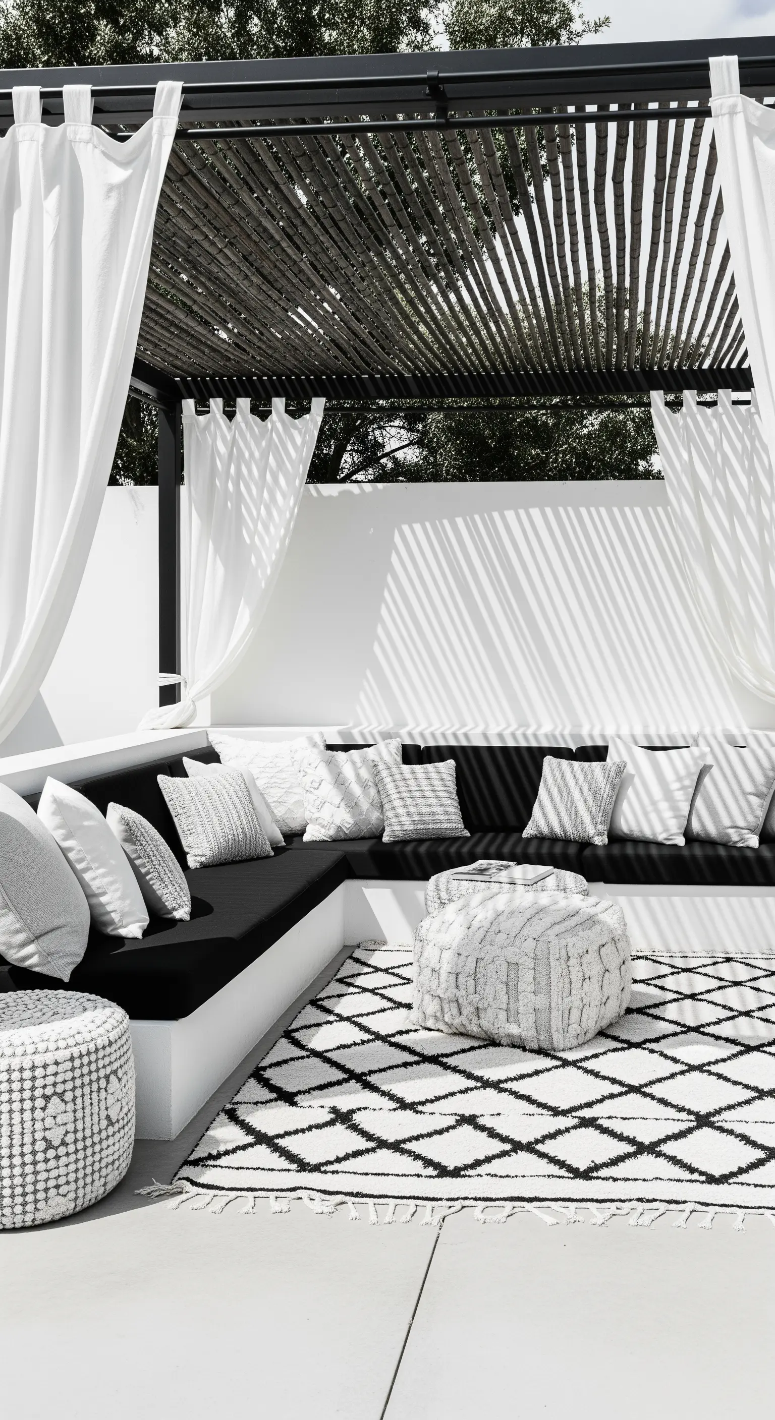 Patio moderno in bianco e nero con divano a L, cuscini a contrasto e tappeto marocchino.