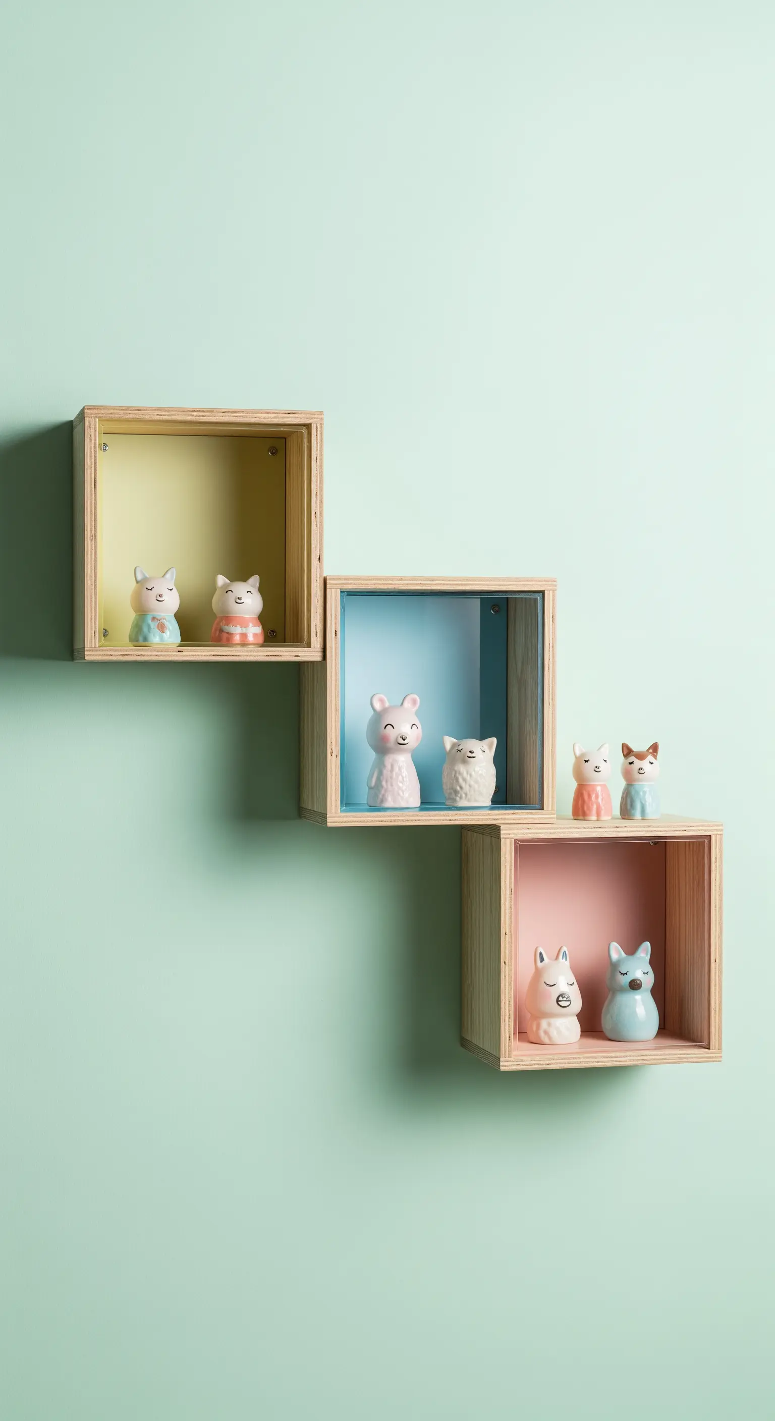 Tre mensole a cubo in legno con il fondo dipinto in colori pastello.