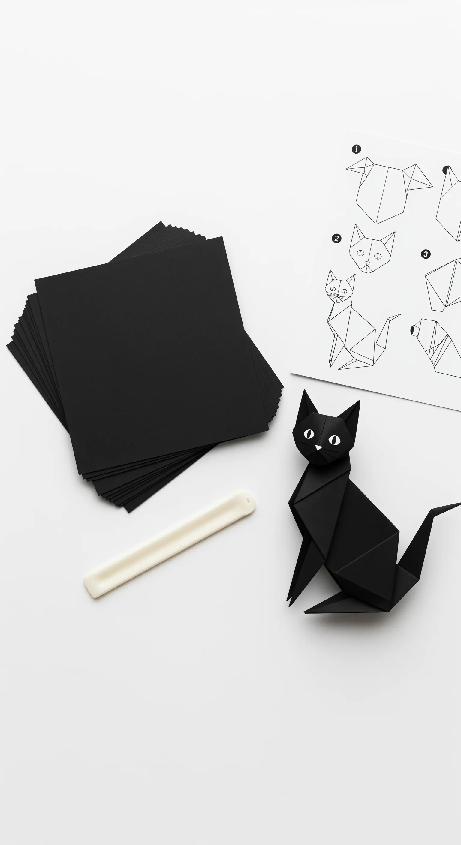 Gatto nero origami realizzato con cartoncino nero, accanto alle istruzioni di piegatura.