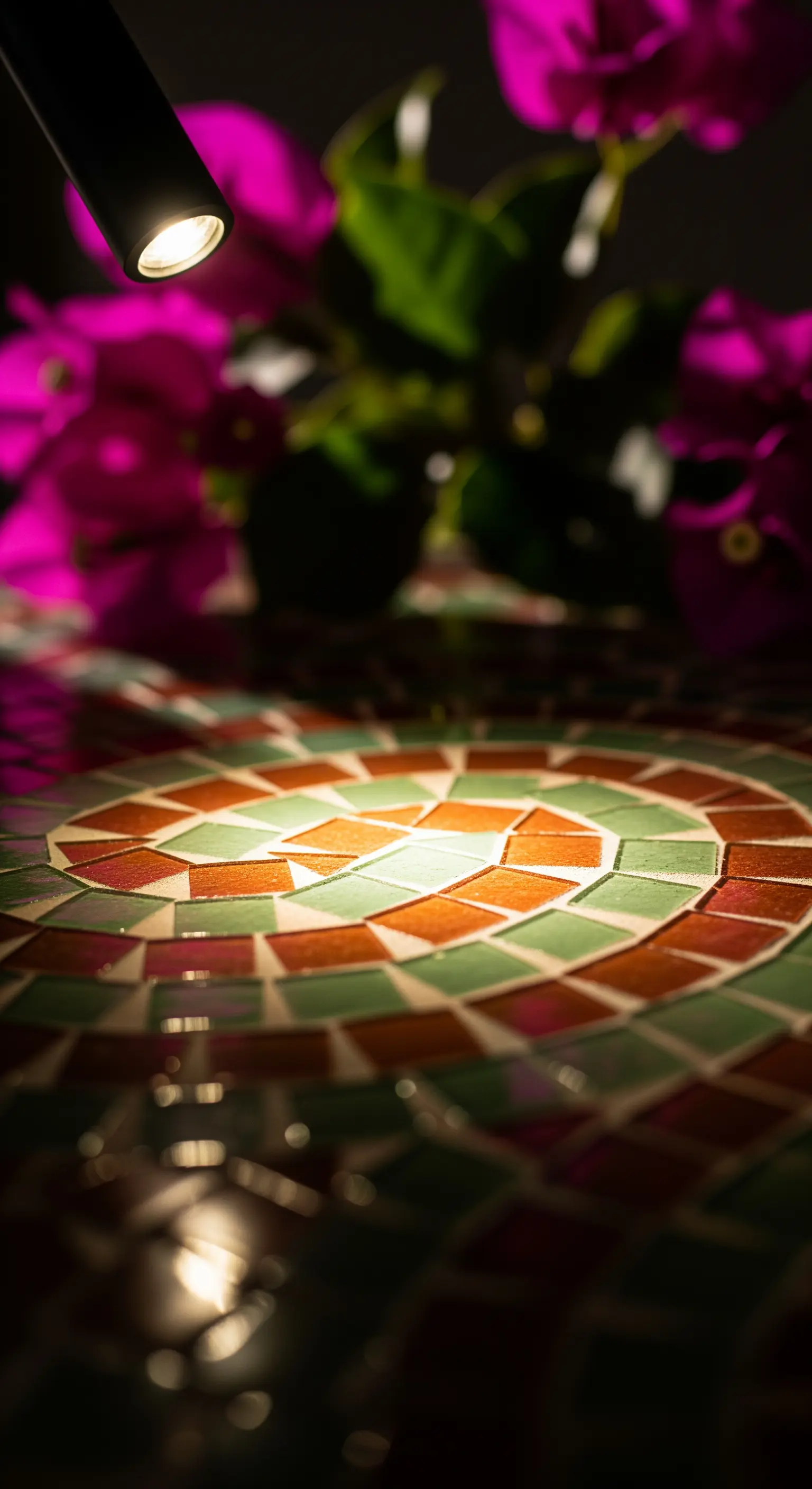 Dettaglio di un tavolo a mosaico illuminato da un faretto direzionabile.