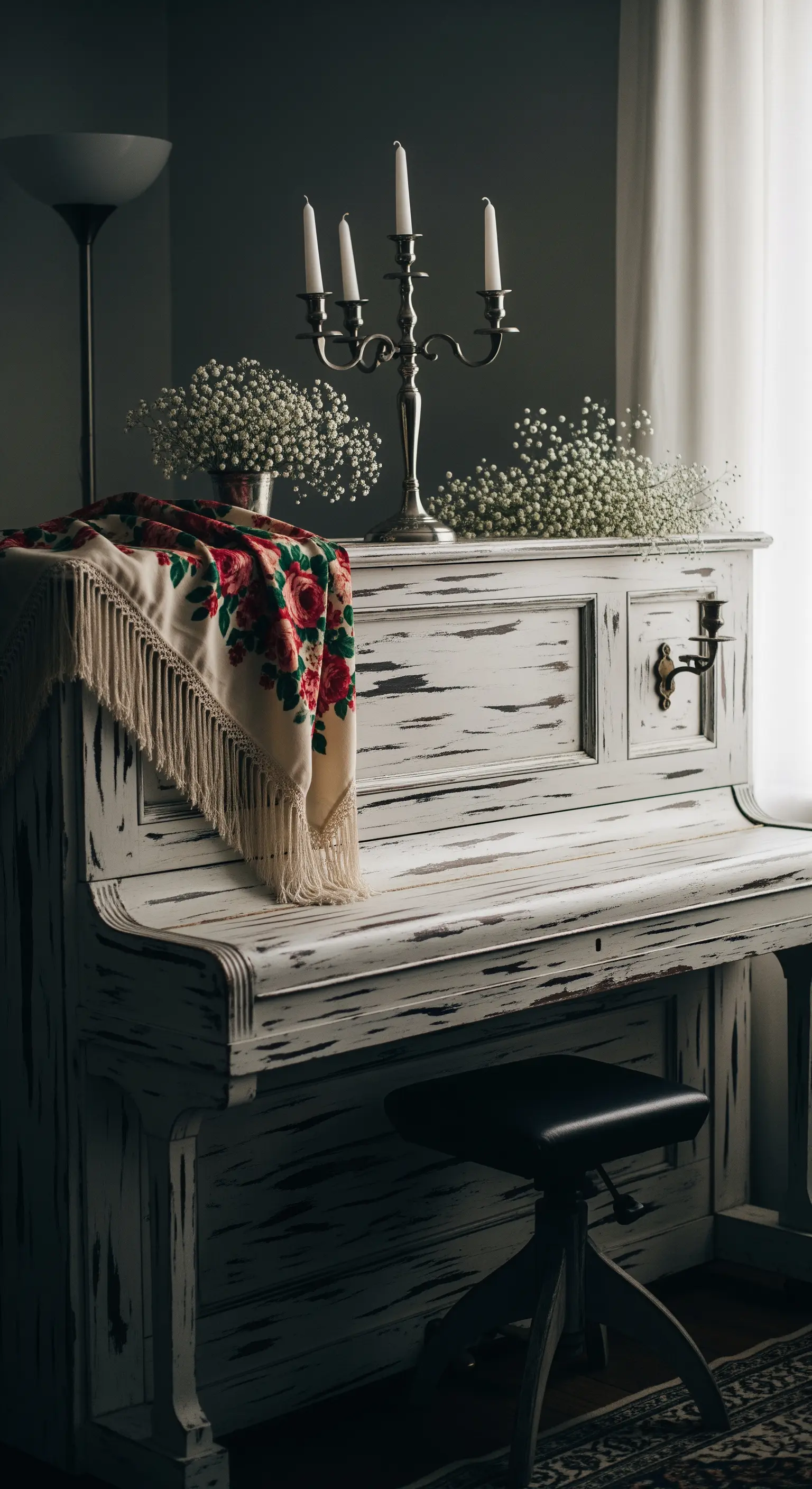 Pianoforte bianco decapé decorato con un candelabro, fiori bianchi e uno scialle floreale.