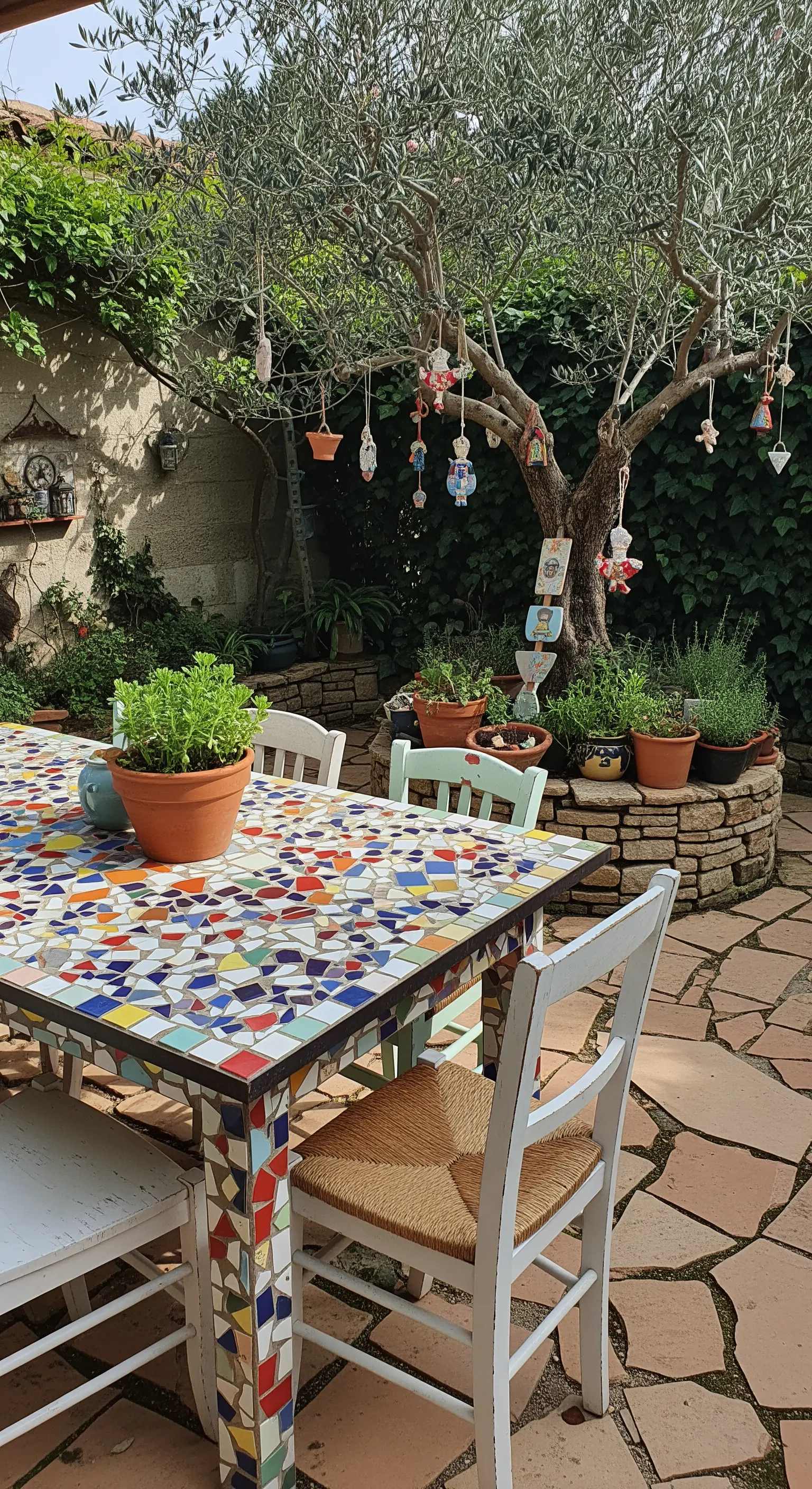 Tavolo da pranzo con piano a mosaico colorato in un giardino con pavimento in pietra.