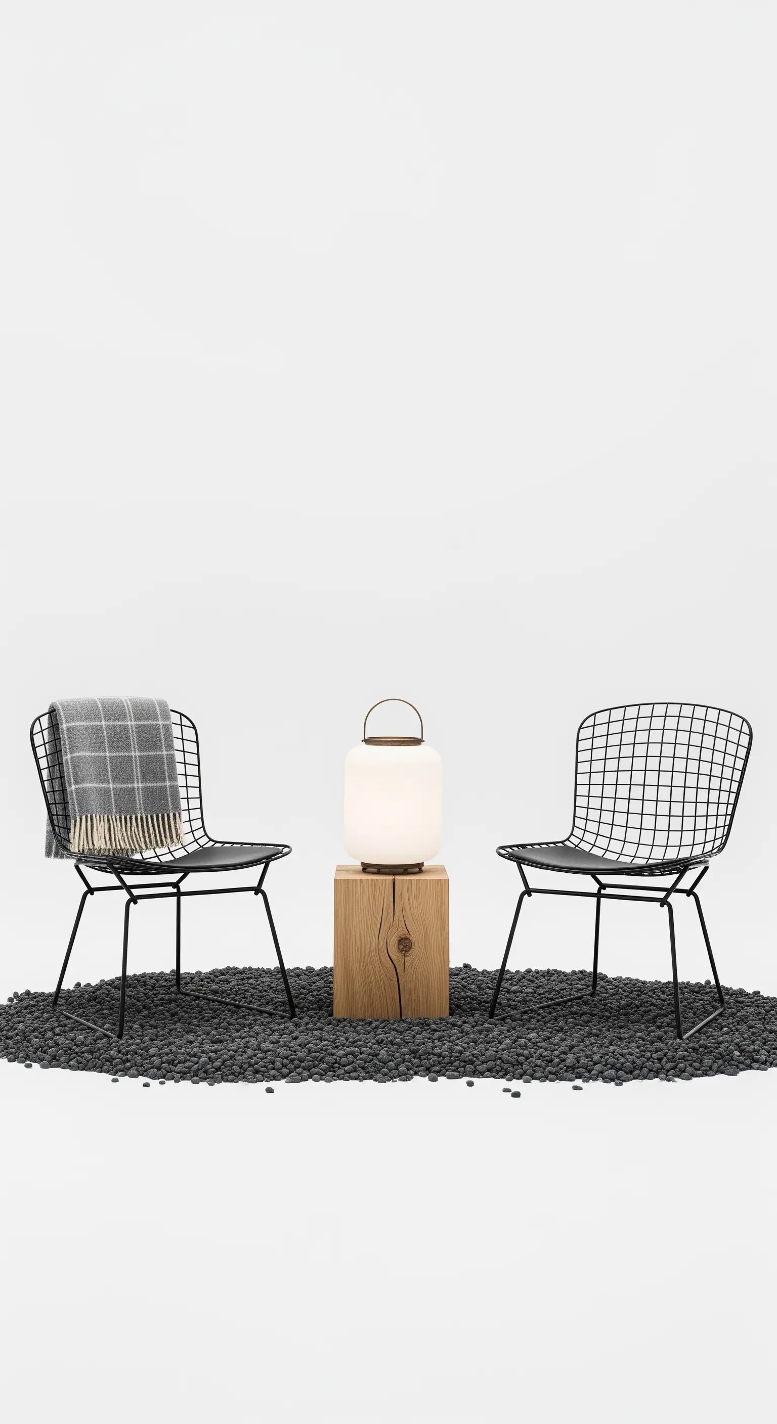 Due sedie minimaliste in metallo nero, una lampada di design su un ceppo di legno.