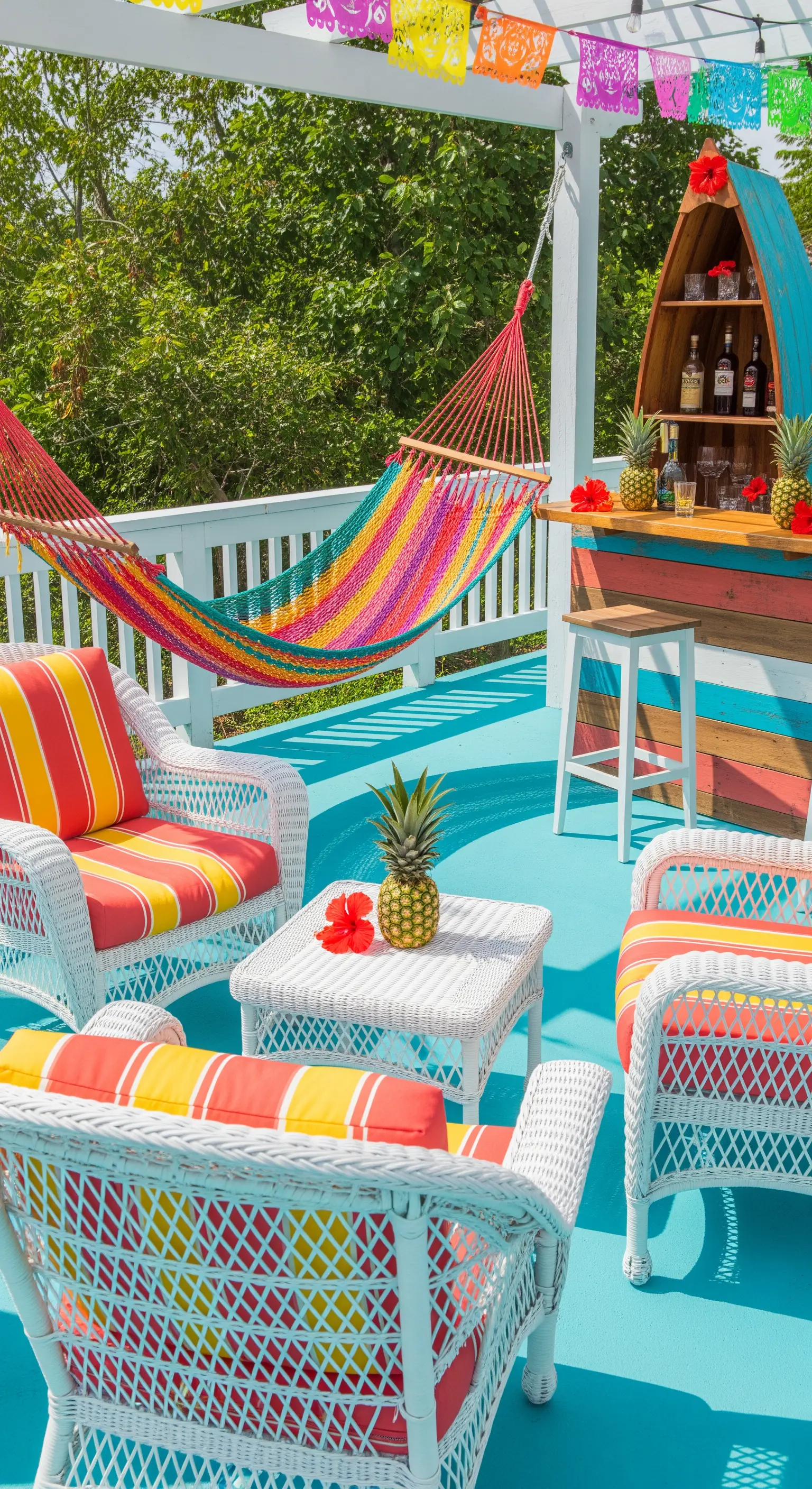 Patio colorato con pavimento turchese, amaca arcobaleno e un bar a forma di barca.