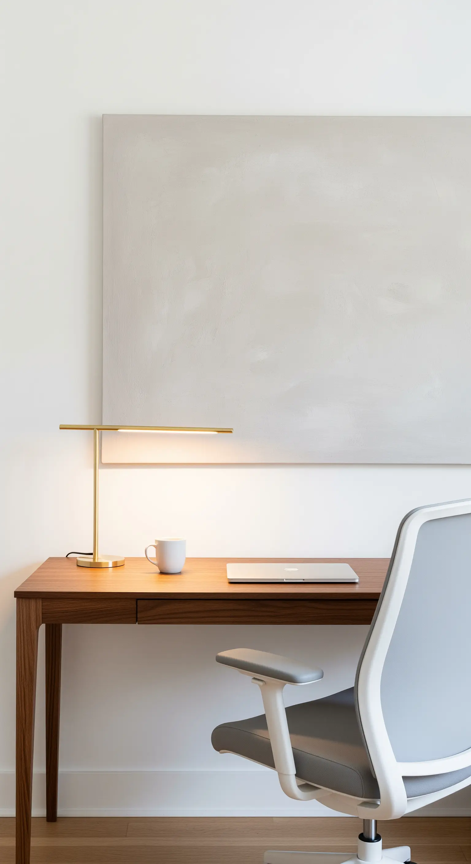 Scrivania minimale con lampada a LED lineare in ottone e sedia ergonomica.