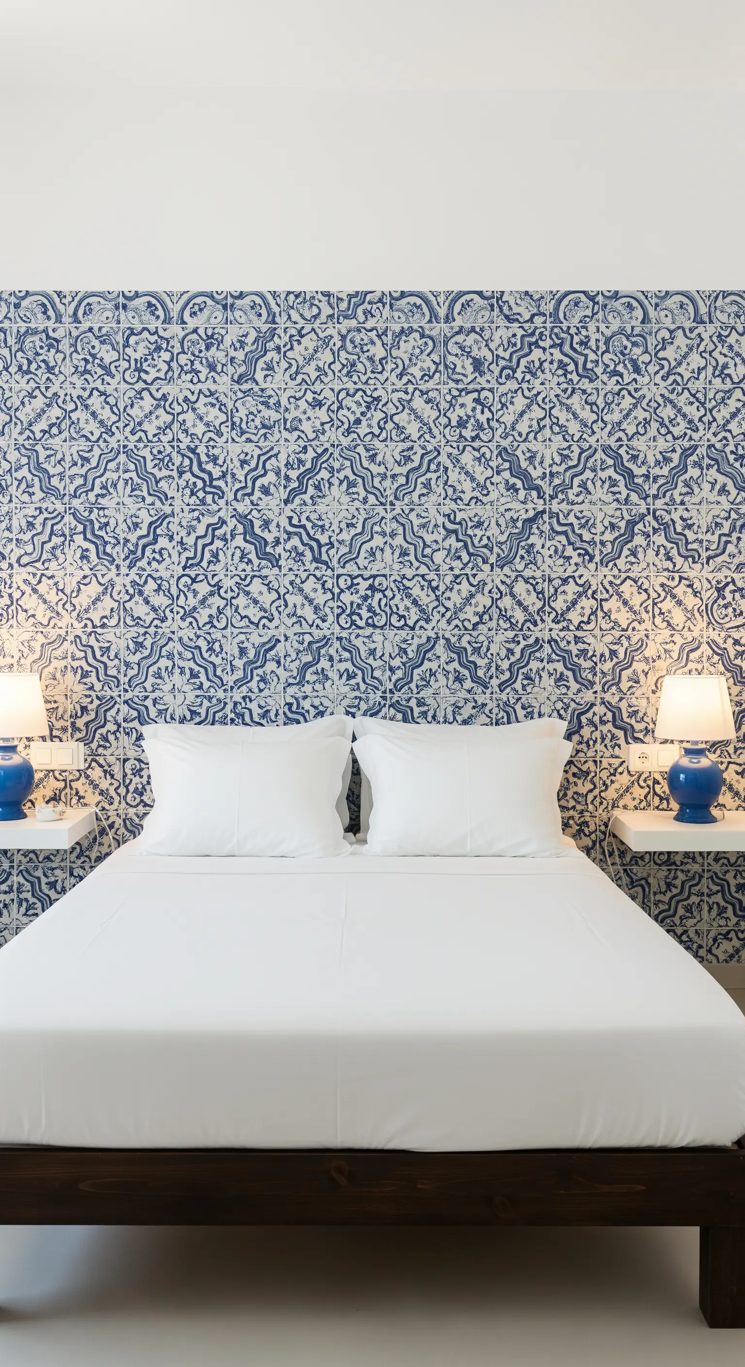 Letto con testiera realizzata con piastrelle in ceramica blu e bianca a motivi geometrici.