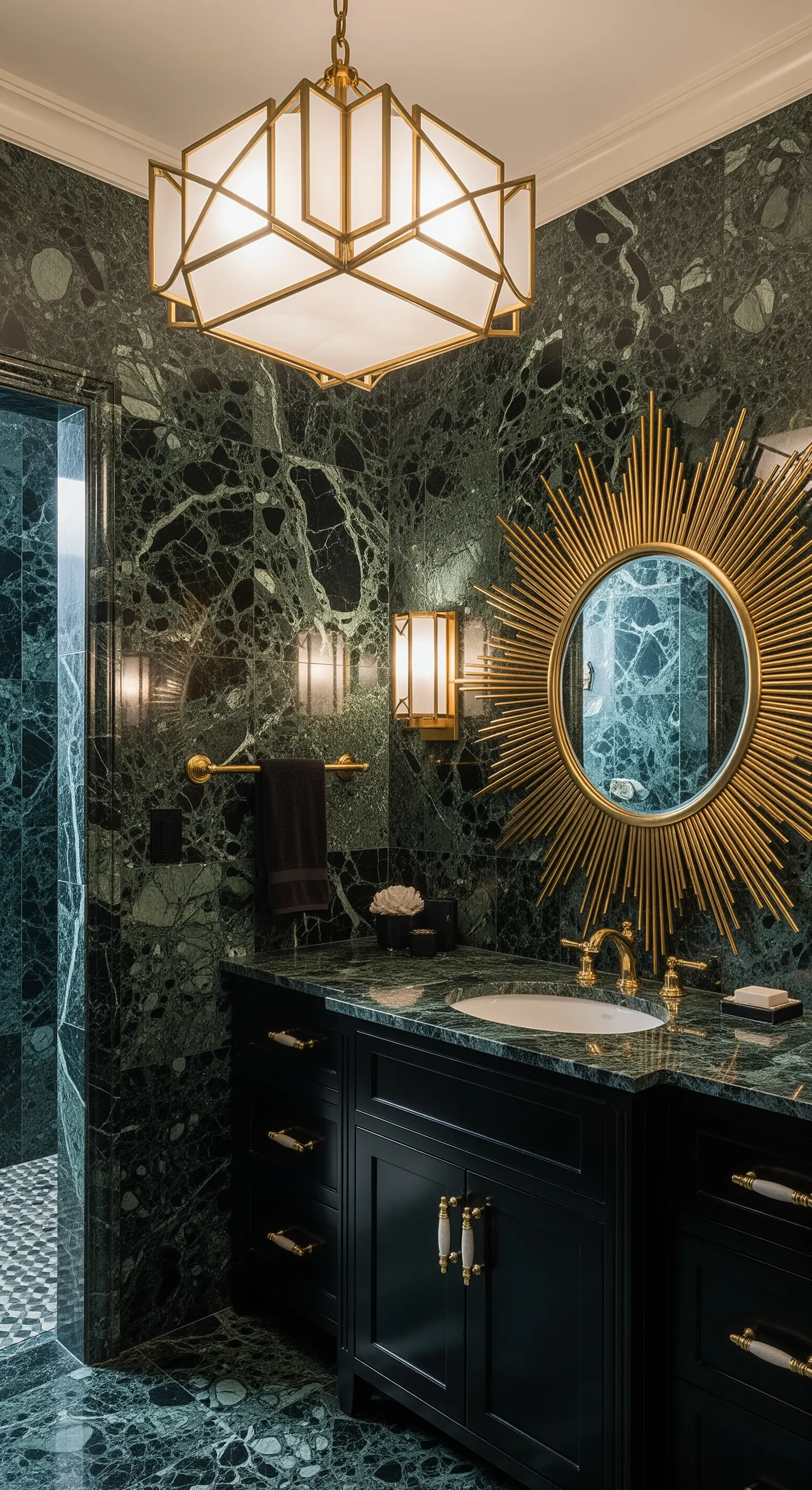 Bagno di lusso con marmo verde scuro, specchio a raggiera dorato e mobile nero.