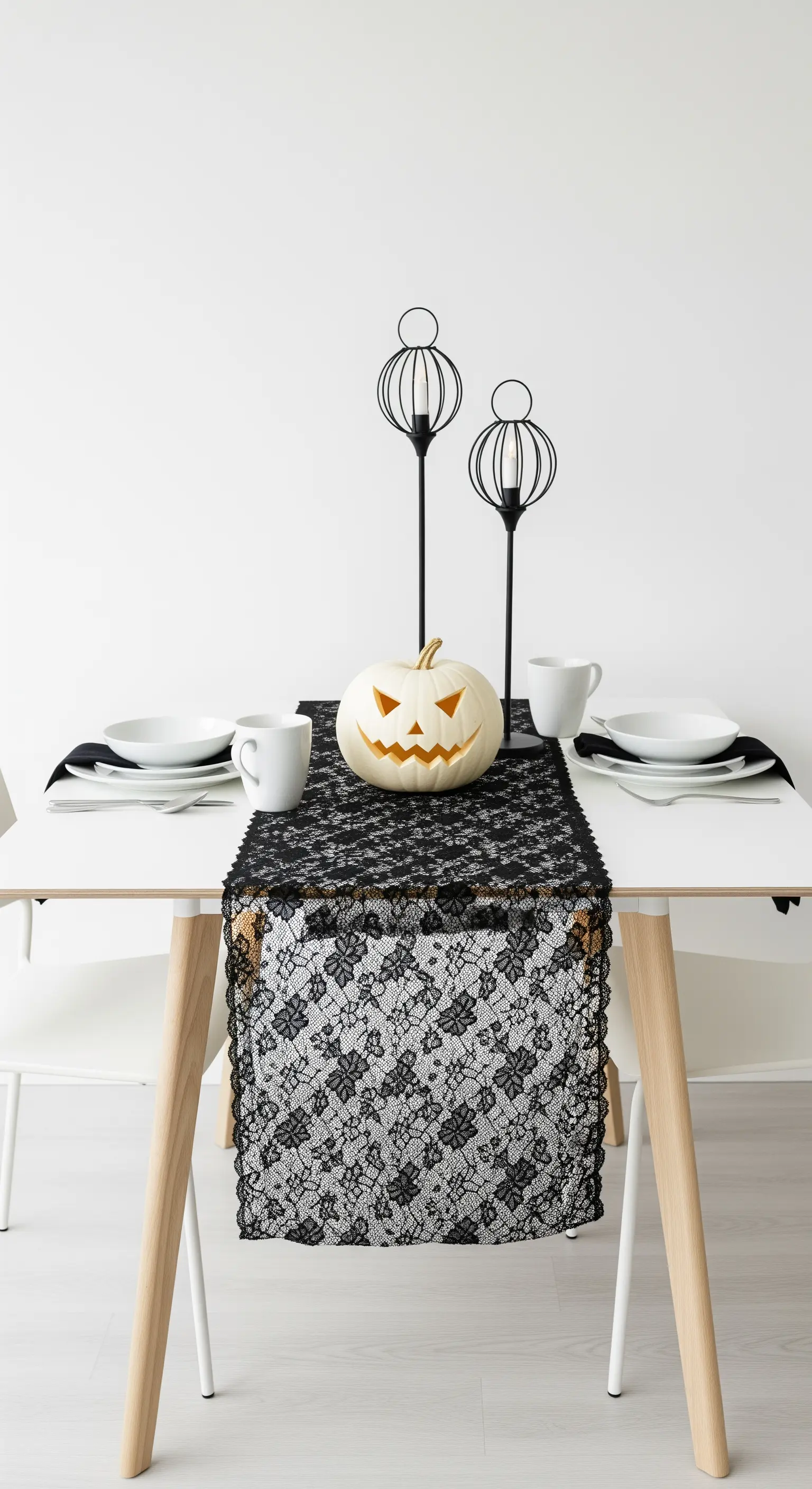 Tavola minimalista per Halloween con runner in pizzo nero e zucca bianca.