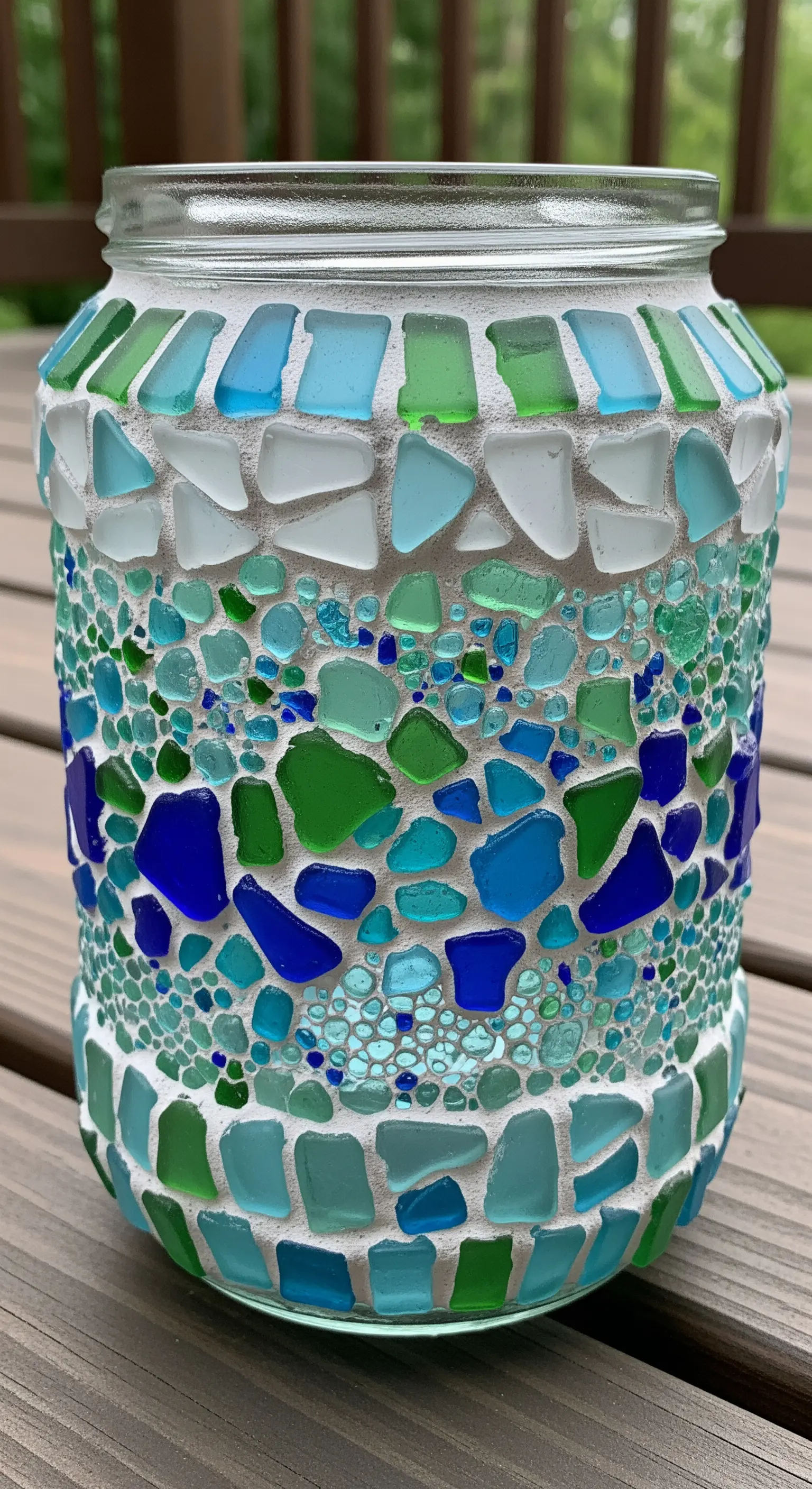 Barattolo di vetro decorato con un mosaico di frammenti di vetro di mare blu, verdi e bianchi.