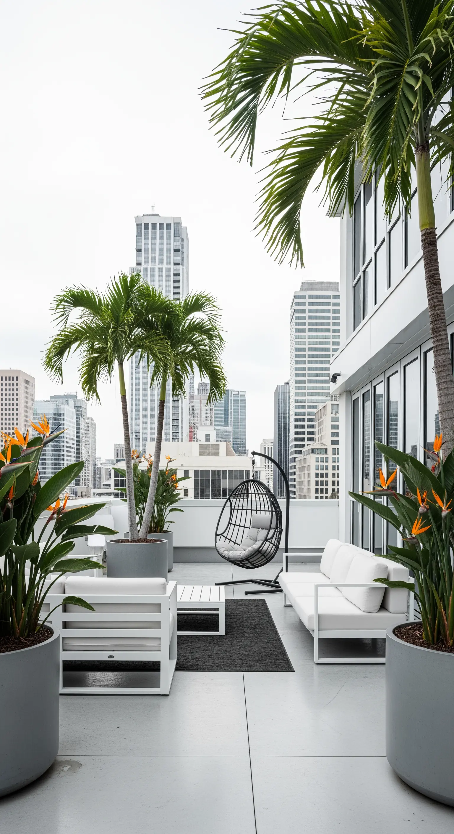 Terrazza urbana minimalista con divani bianchi, palme in vaso e una poltrona sospesa.