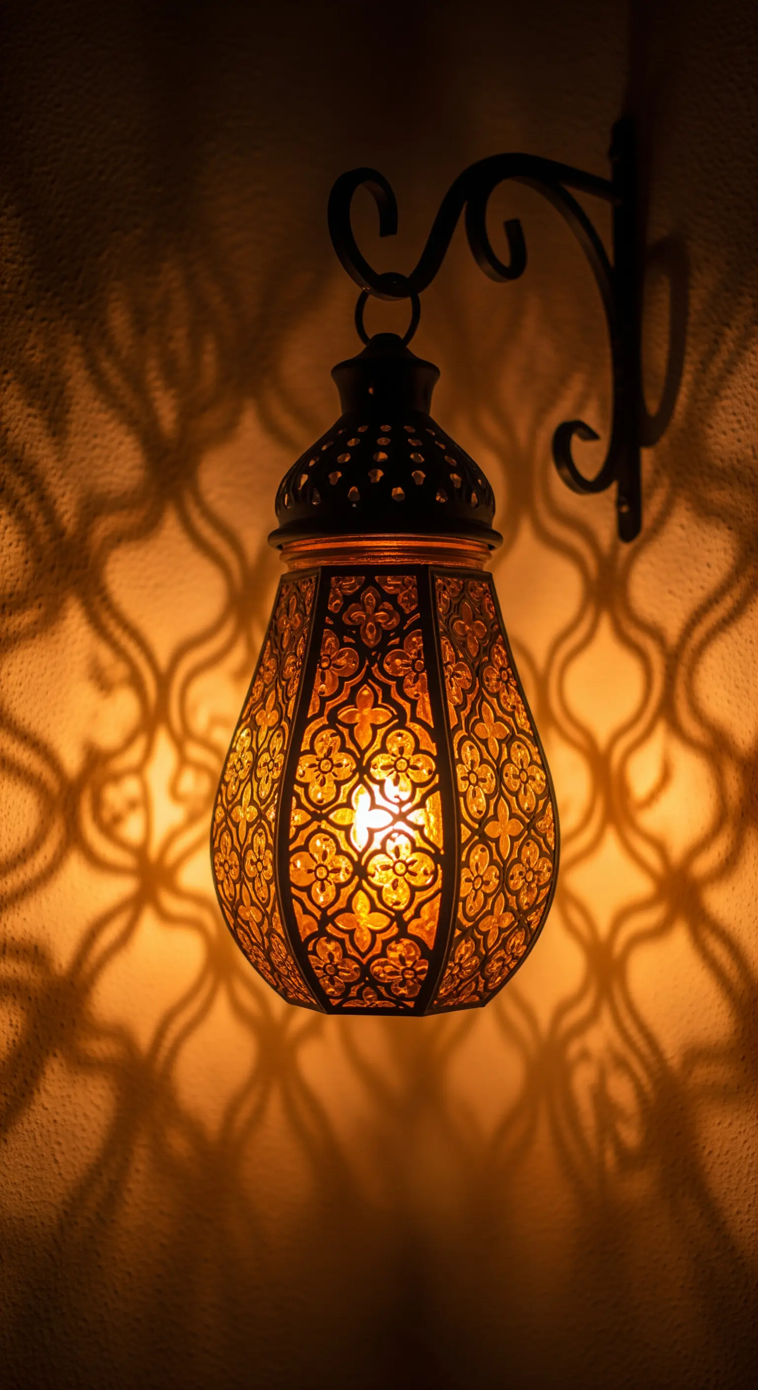 Lanterna marocchina in metallo intagliato che proietta ombre decorative sulla parete.