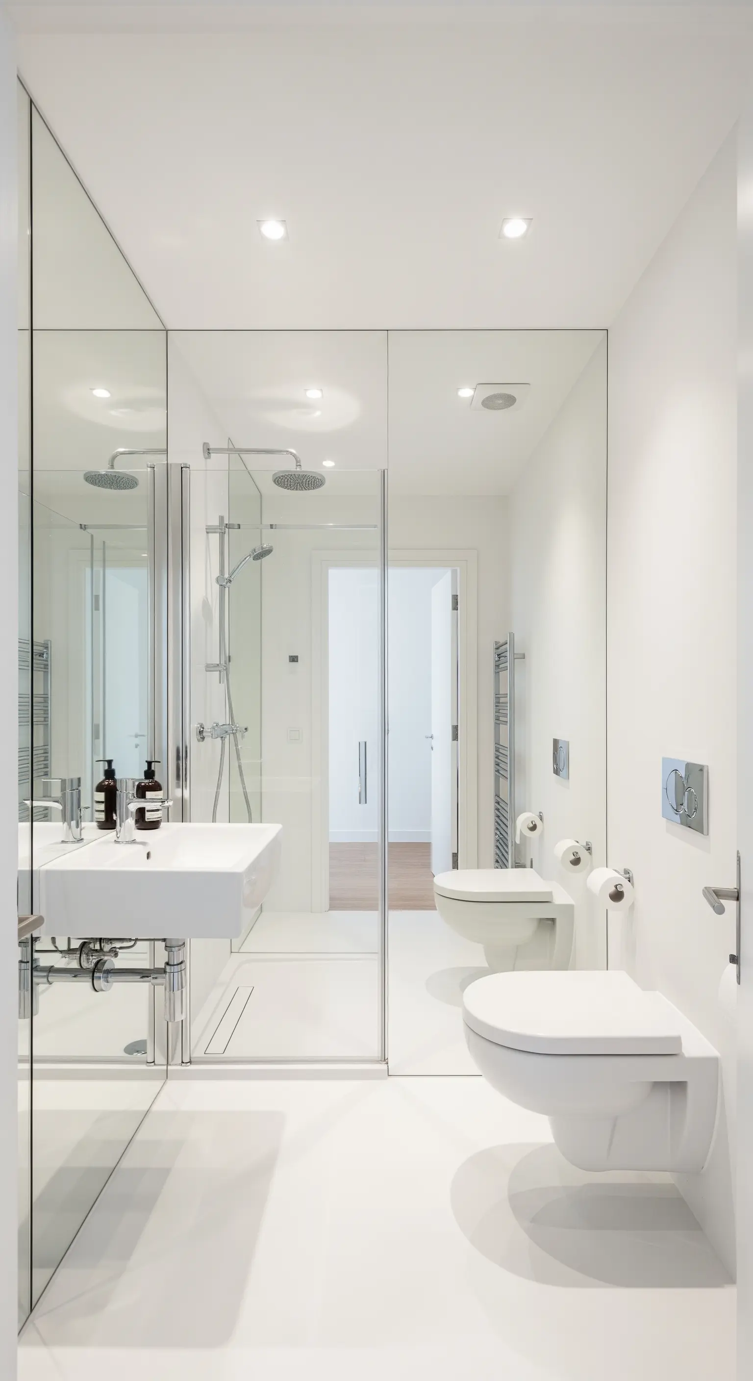 Bagno stretto e lungo con un'intera parete rivestita di specchi che raddoppiano lo spazio.