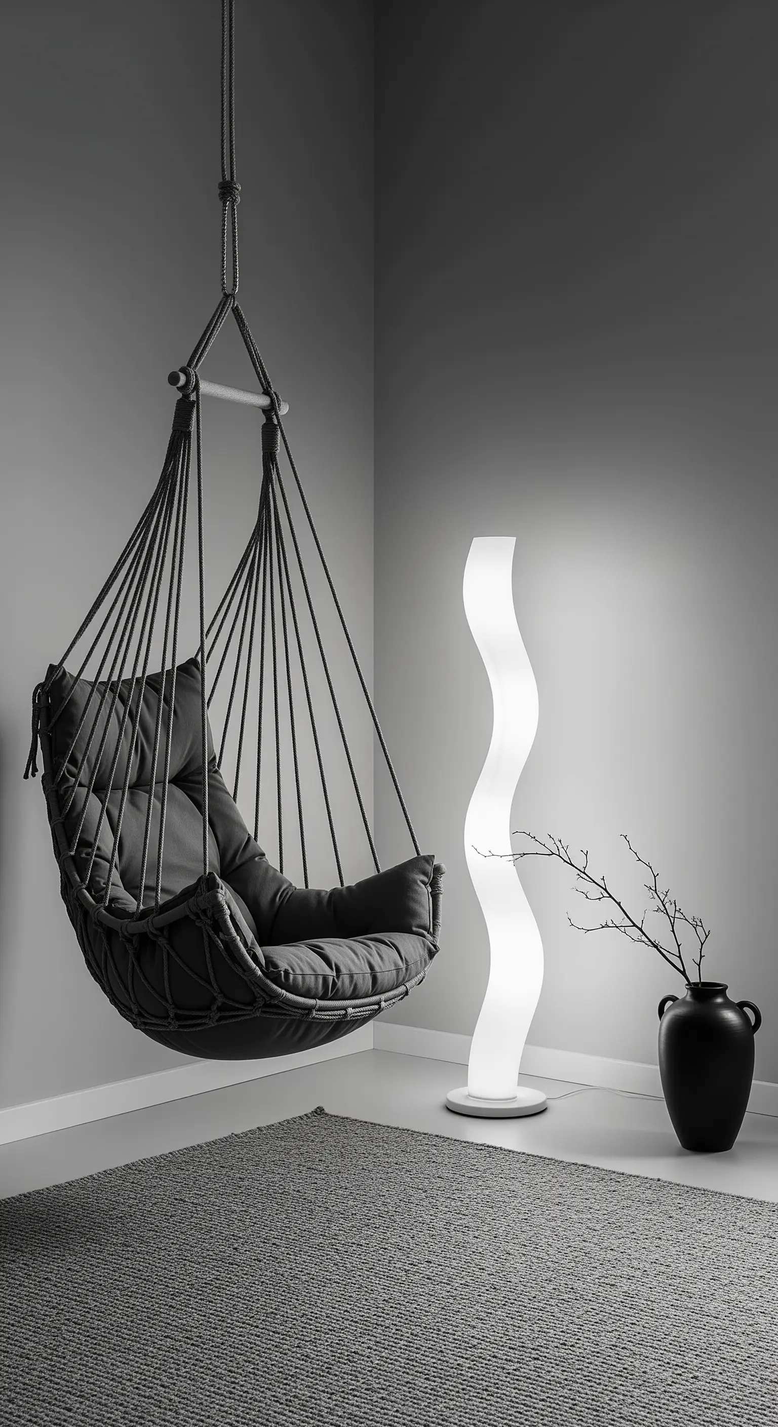 Poltrona sospesa nera dal design moderno accanto a una lampada da terra bianca sinuosa.