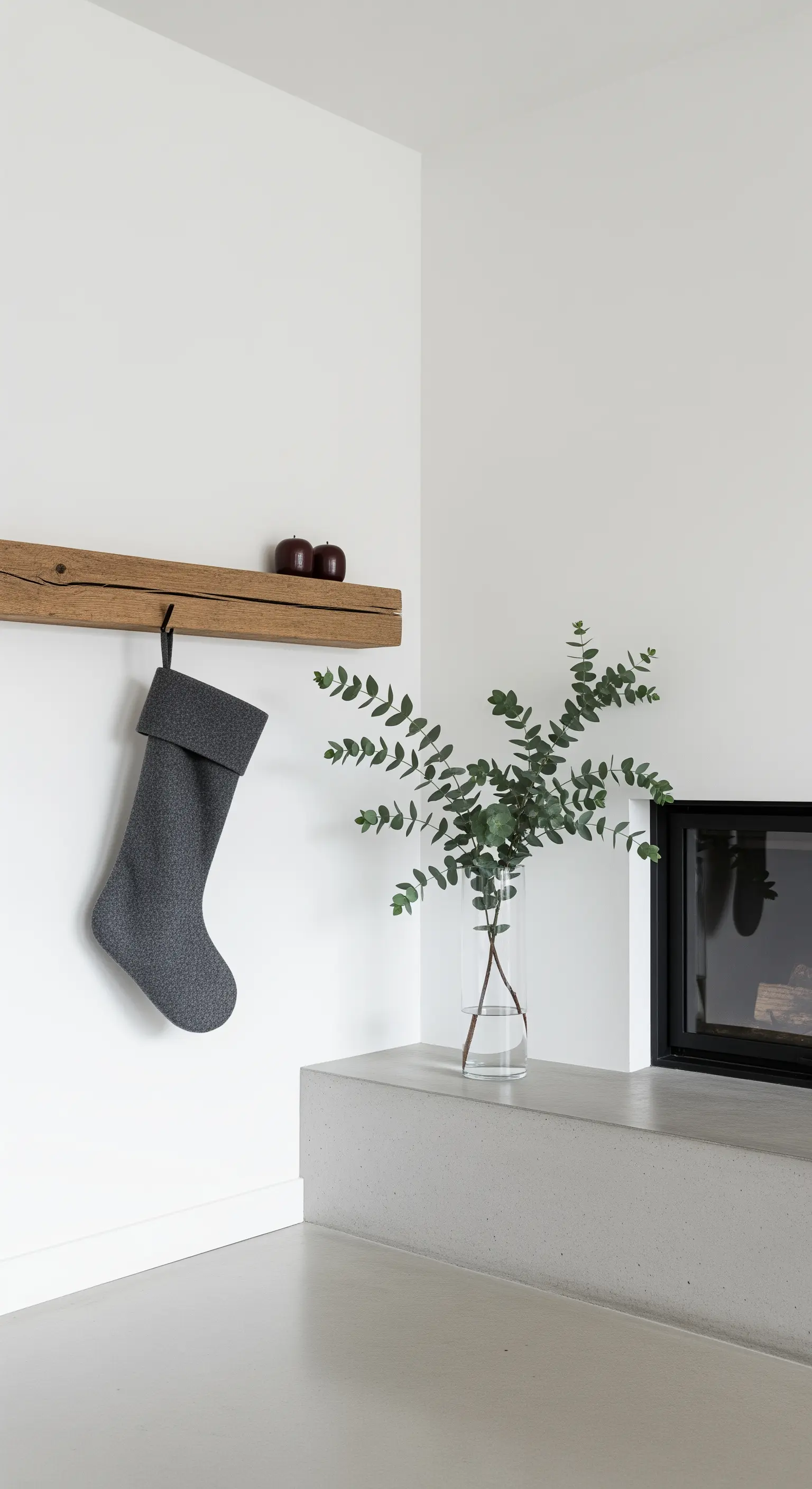 Angolo minimalista con mensola in legno, una calza grigia e un vaso con eucalipto.