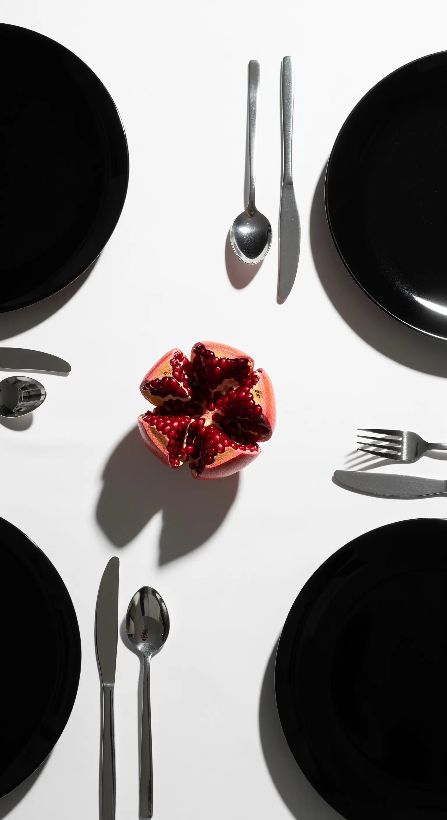 Tavola in bianco e nero con un melograno rosso aperto al centro