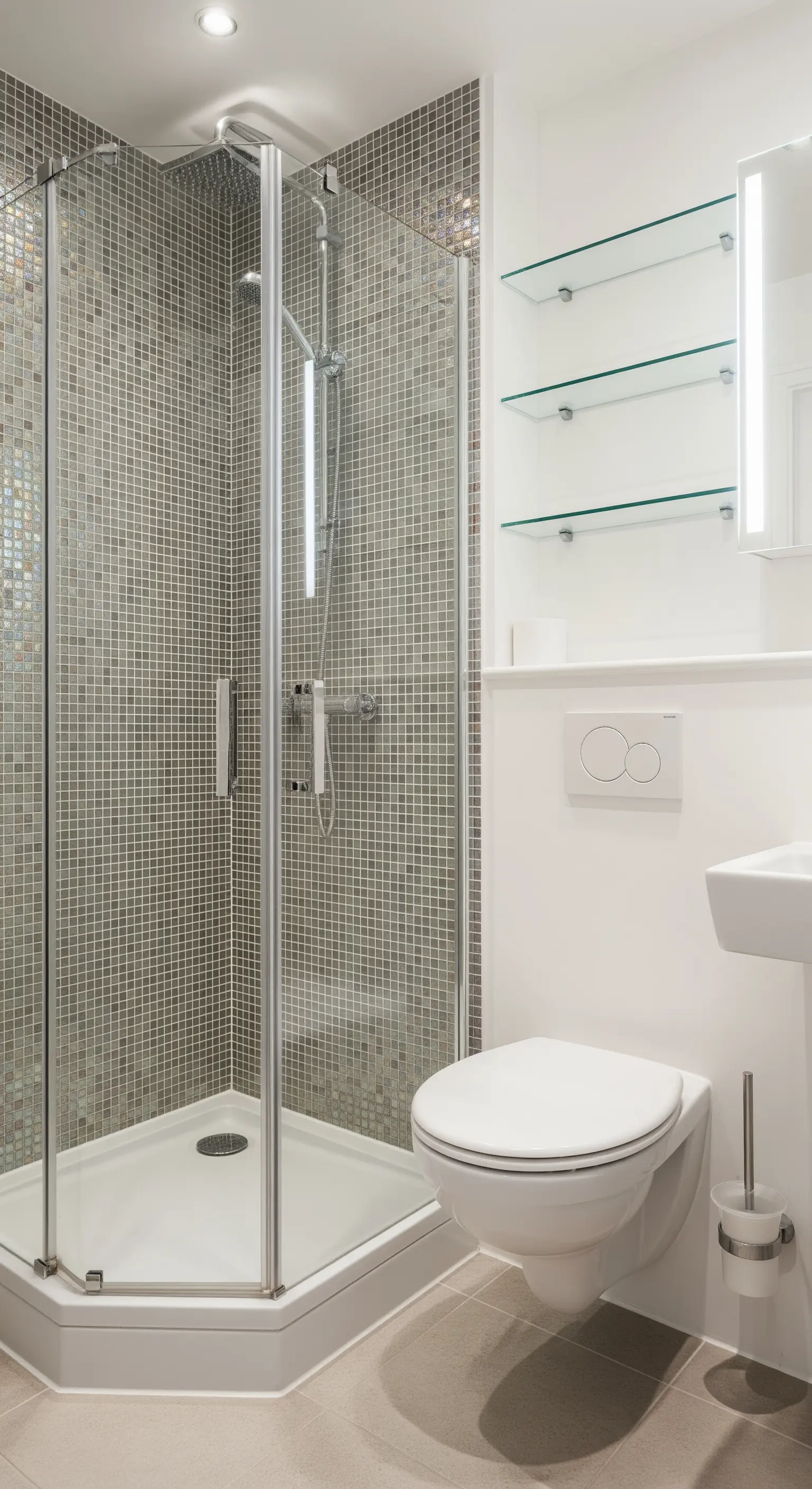Doccia angolare rivestita in mosaico grigio perla con mensole in vetro.