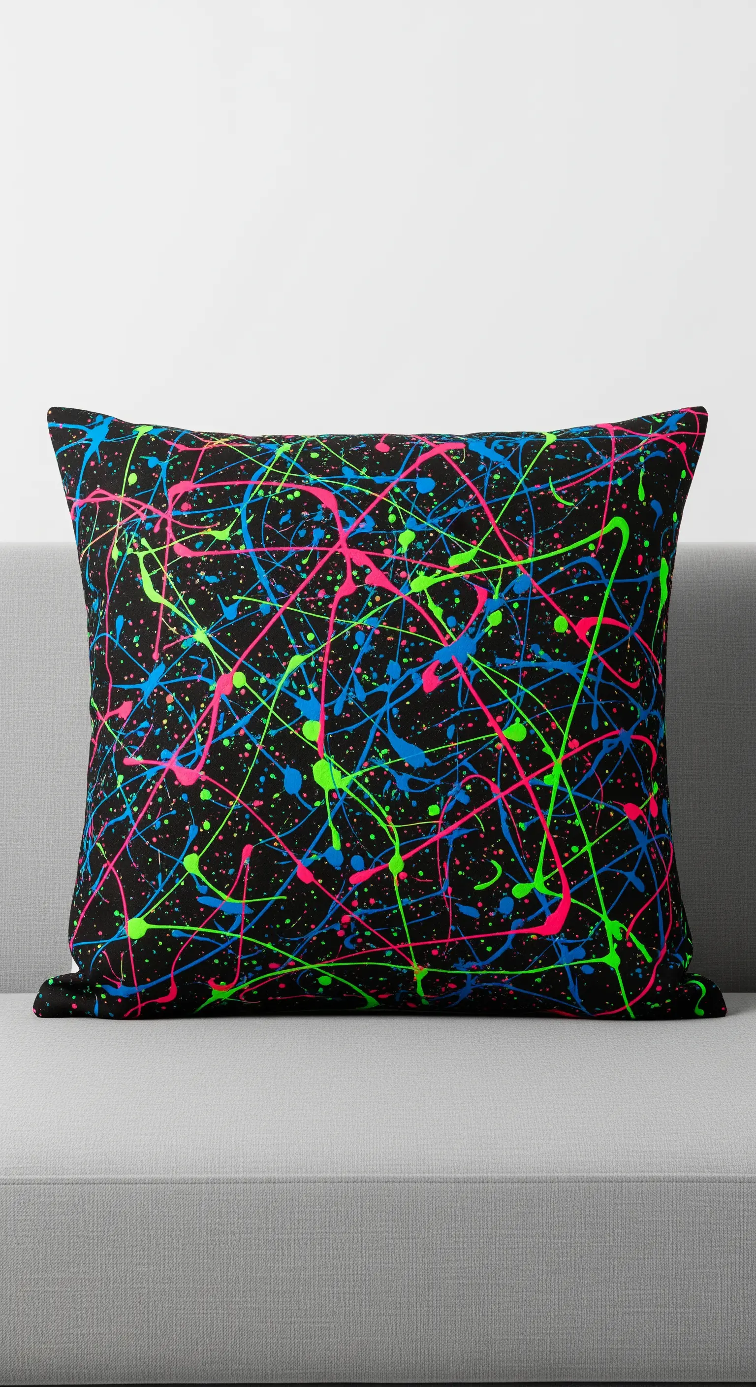 Cuscino nero con schizzi di vernice fluo blu, verde e rosa in stile action painting.