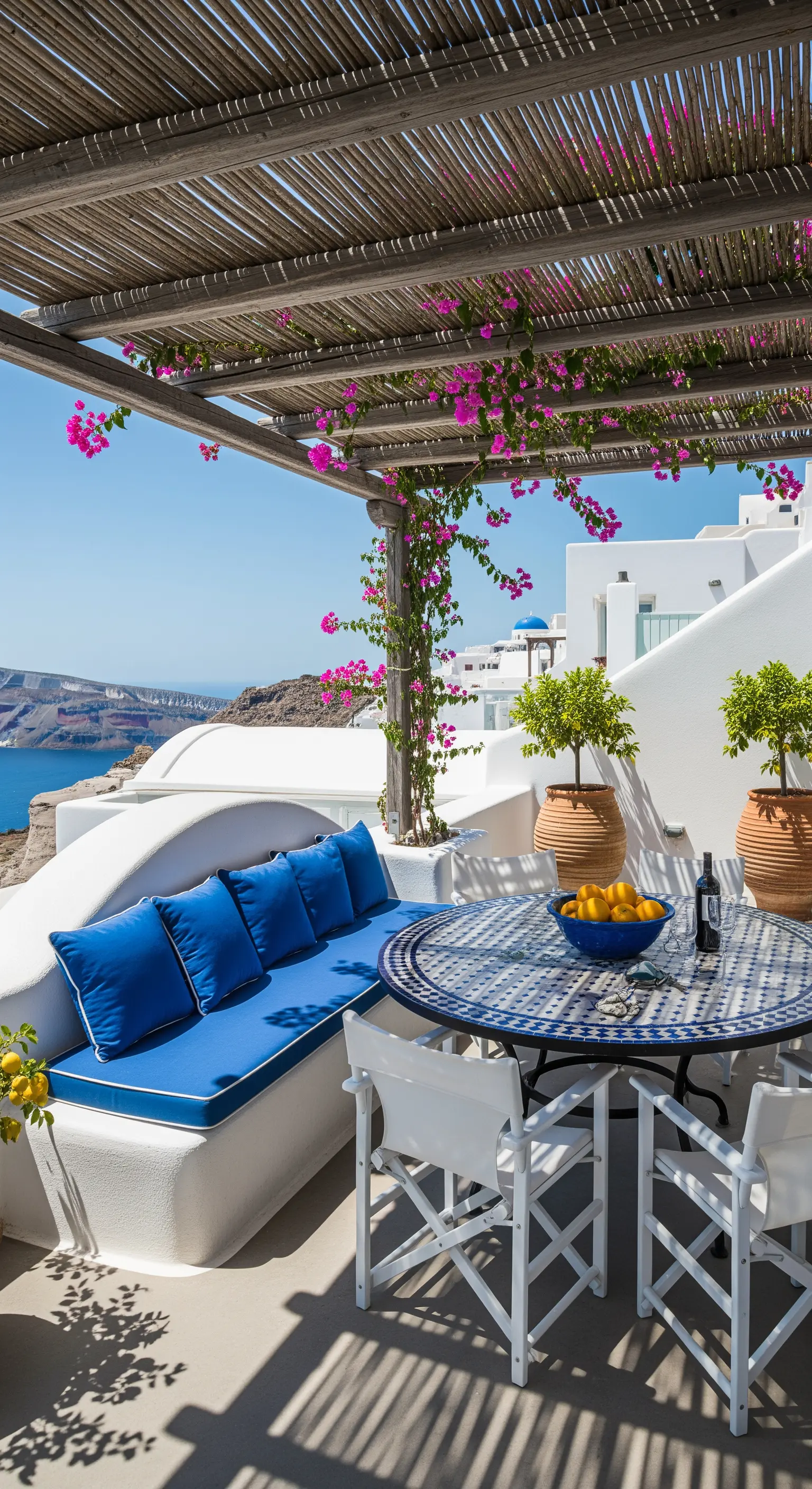 Terrazza mediterranea con divano in muratura, cuscini blu e tavolo a mosaico.