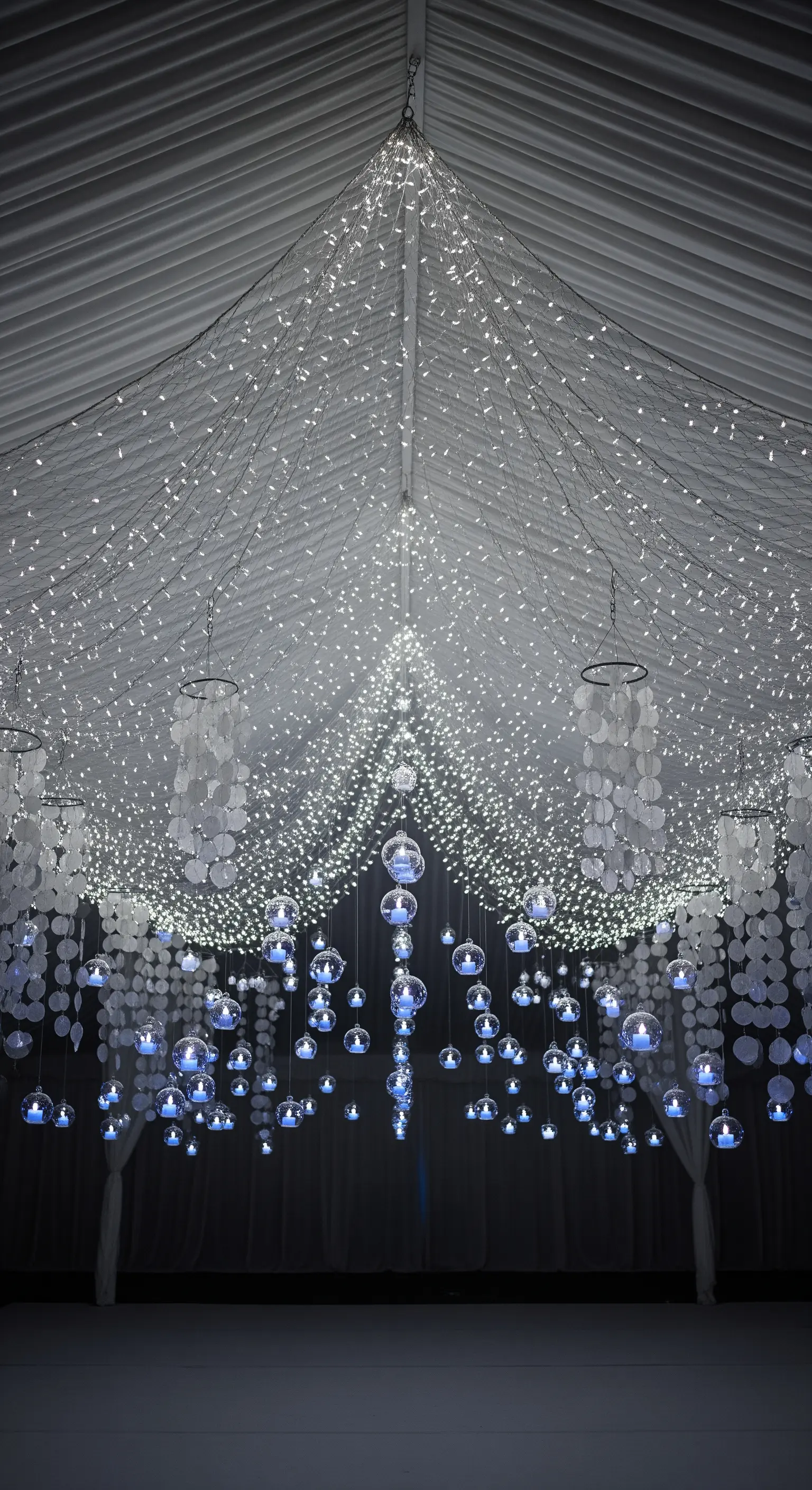 Soffitto decorato con una cascata di lucine e bolle di vetro con candele blu