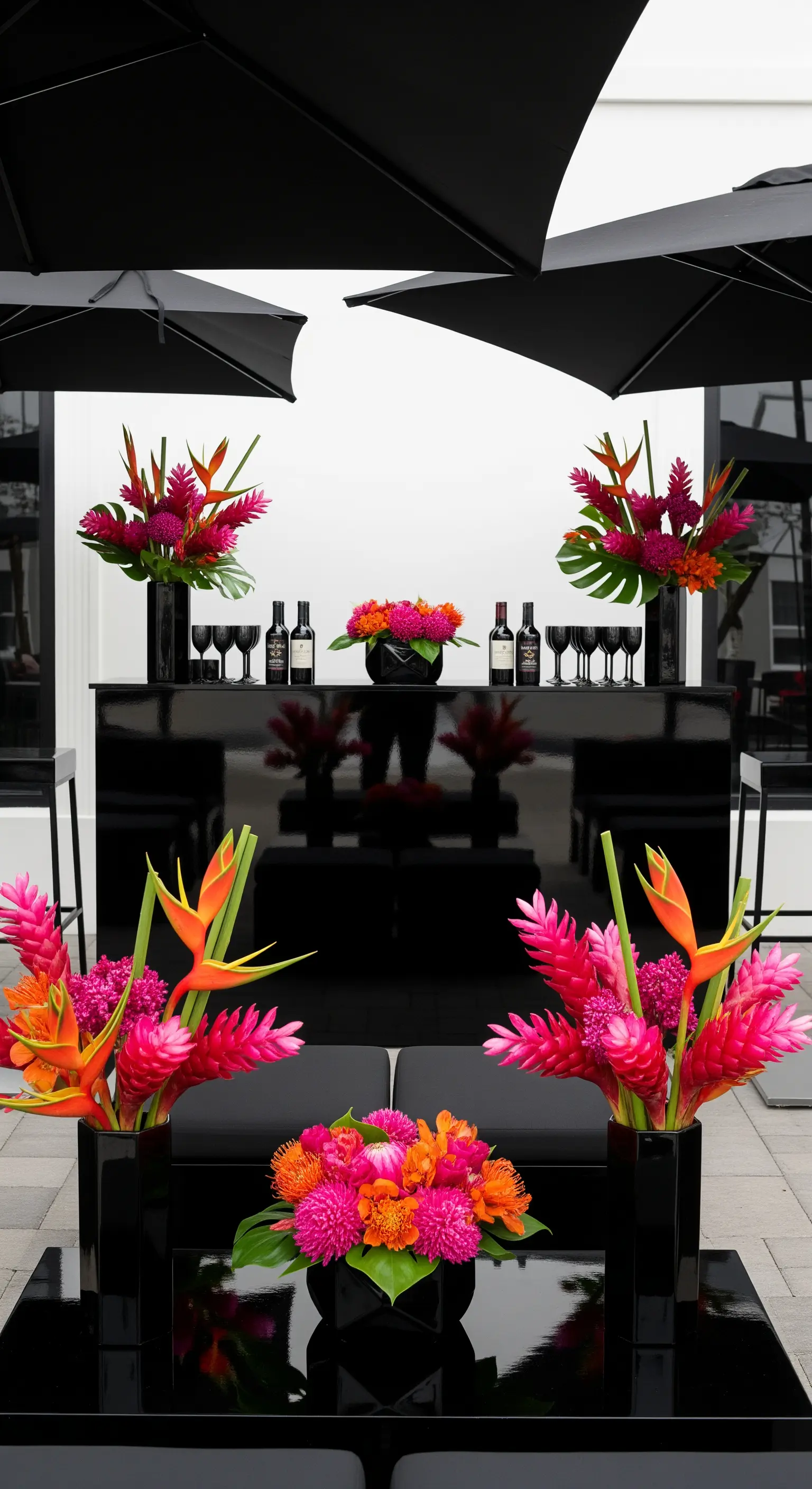Allestimento moderno con arredi neri e fiori tropicali fucsia e arancioni come accento di colore