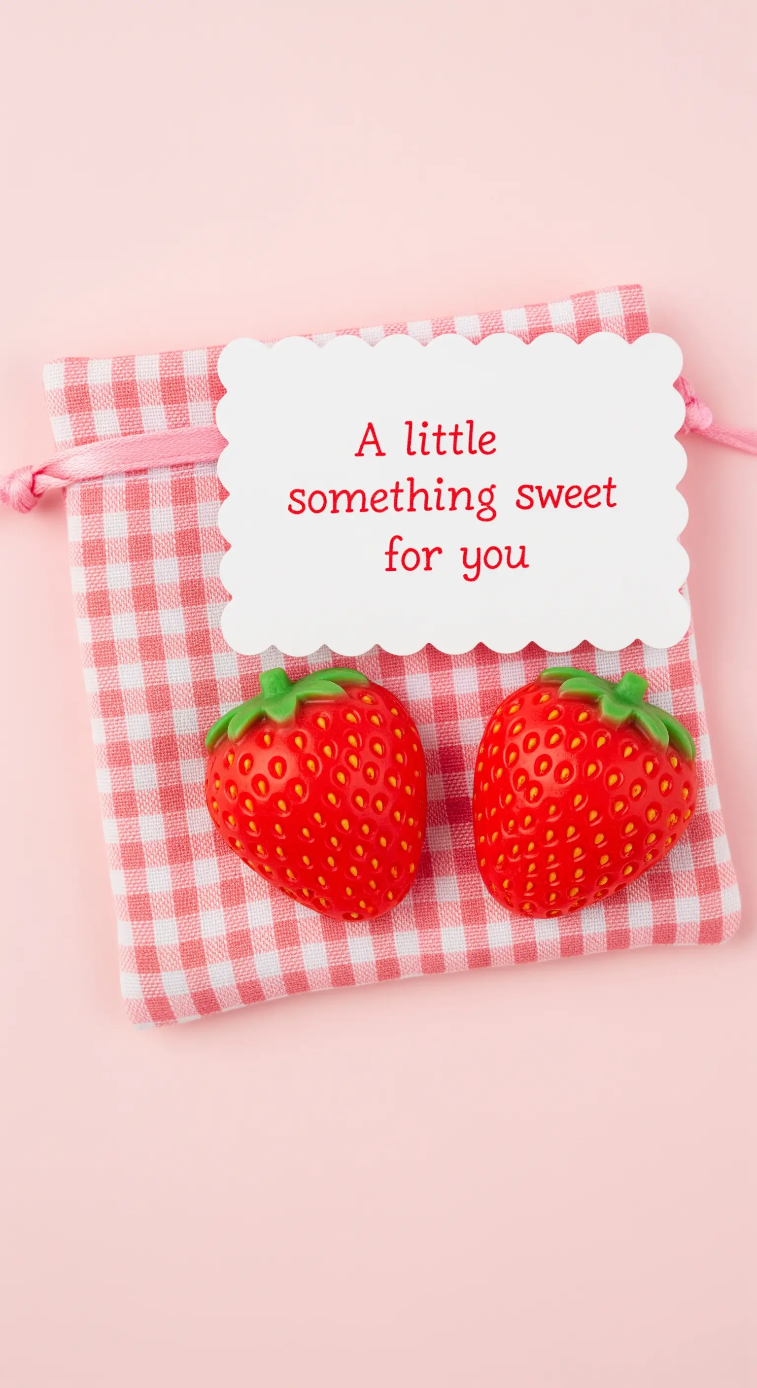 Sacchetto a quadretti rosa e bianchi con saponette a forma di fragola e un biglietto.