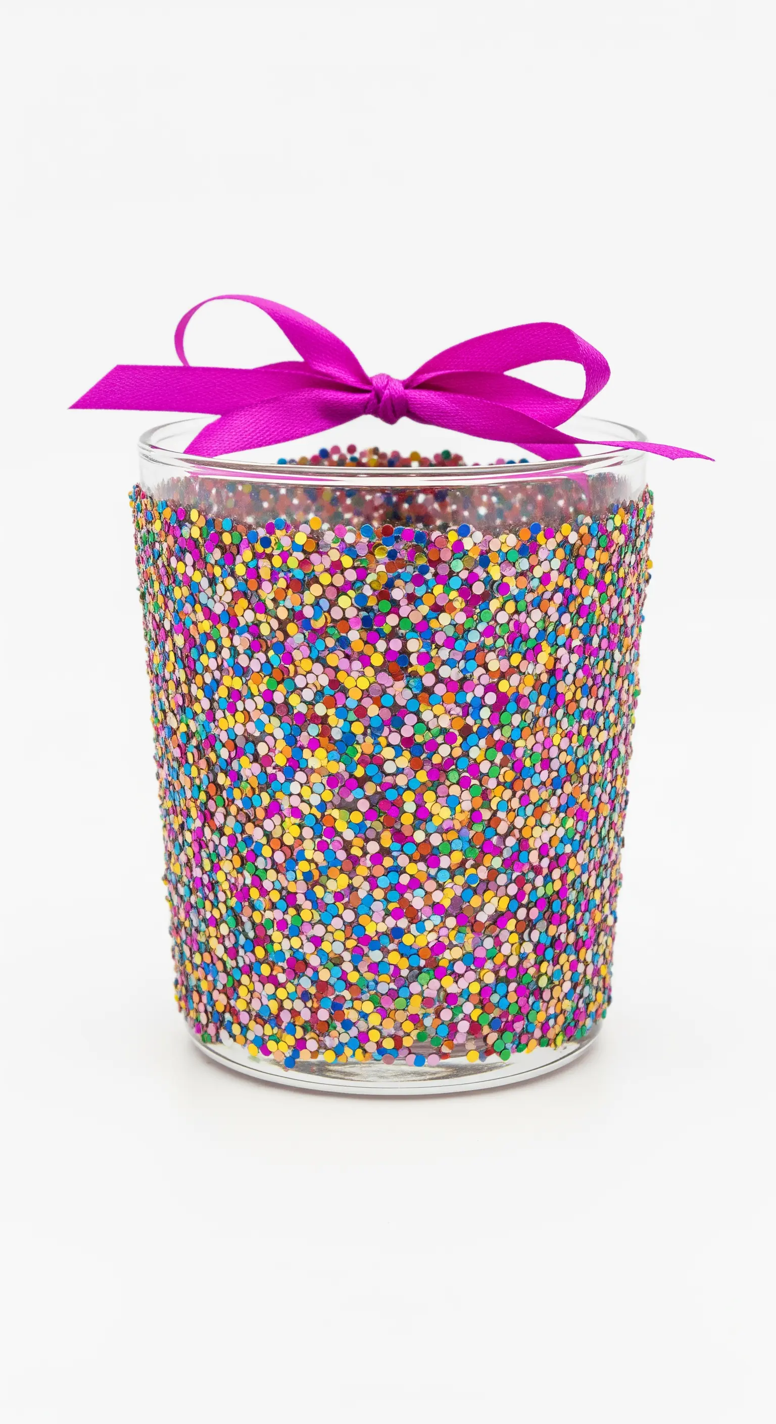 Bicchiere ricoperto di coriandoli glitterati multicolore con un fiocco fucsia.