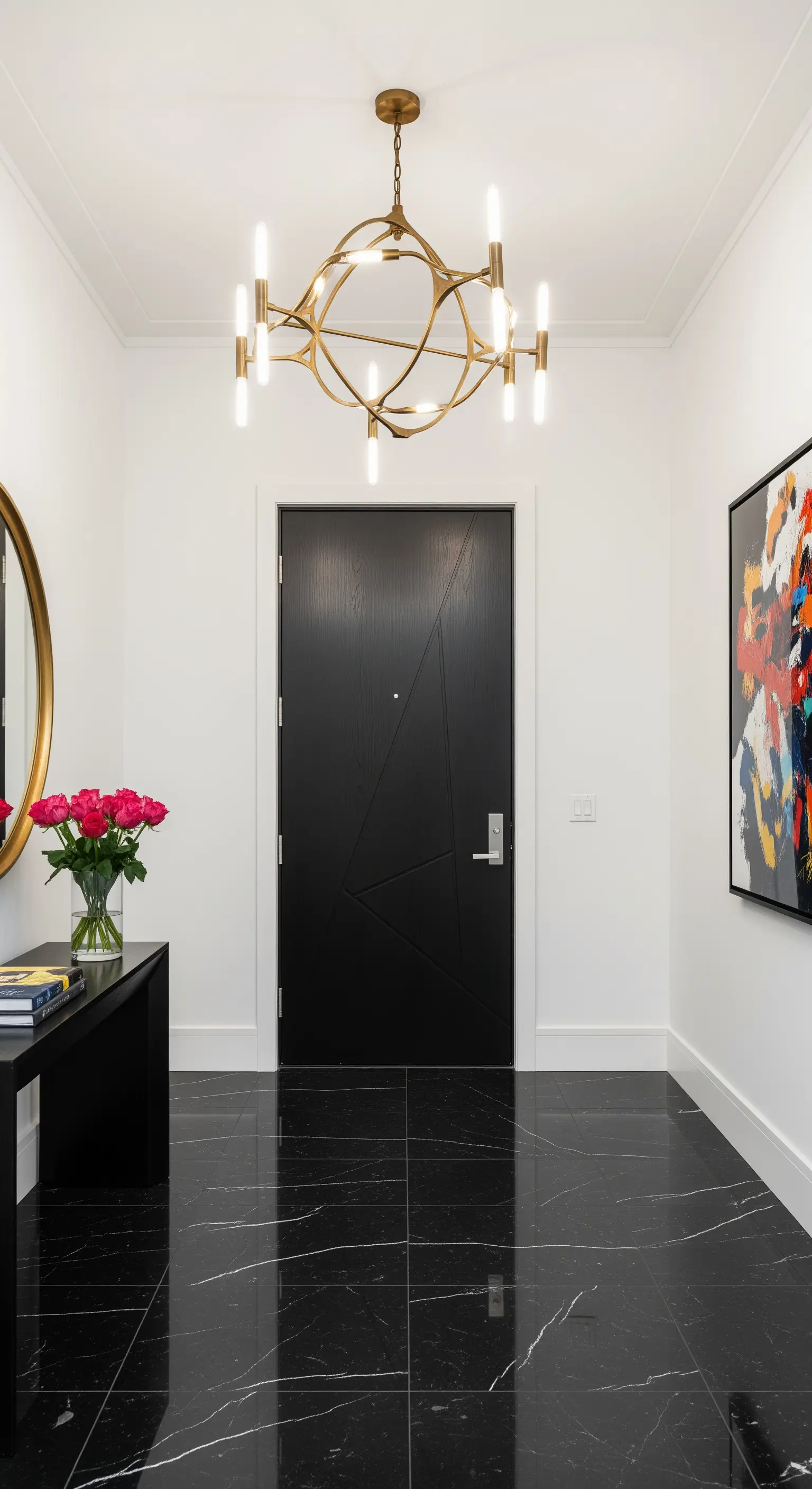 Ingresso moderno con pavimento in marmo nero, porta nera e lampadario scultoreo in ottone.