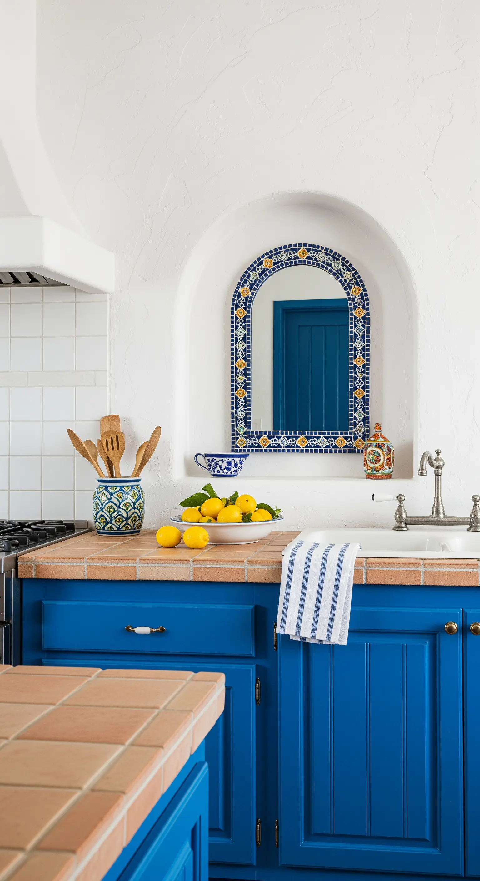 Cucina blu in stile mediterraneo con specchio a mosaico in una nicchia ad arco.