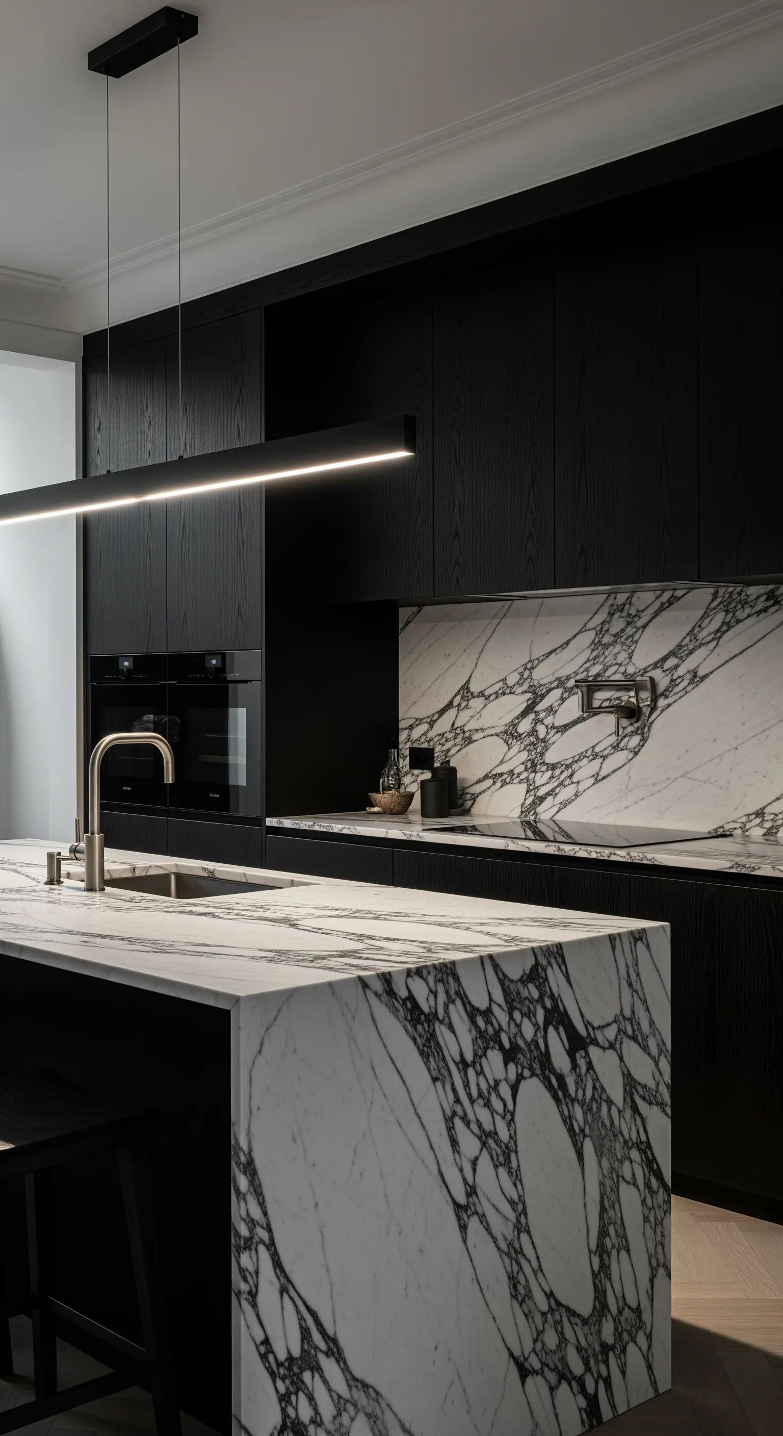 Cucina total black con isola e paraschizzi in marmo con venature nere molto evidenti.