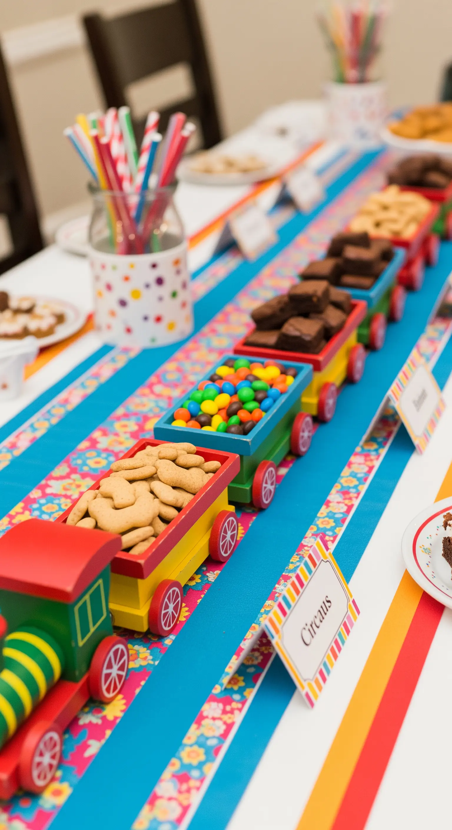 Trenino giocattolo colorato usato come contenitore per biscotti e caramelle su un tavolo da festa.