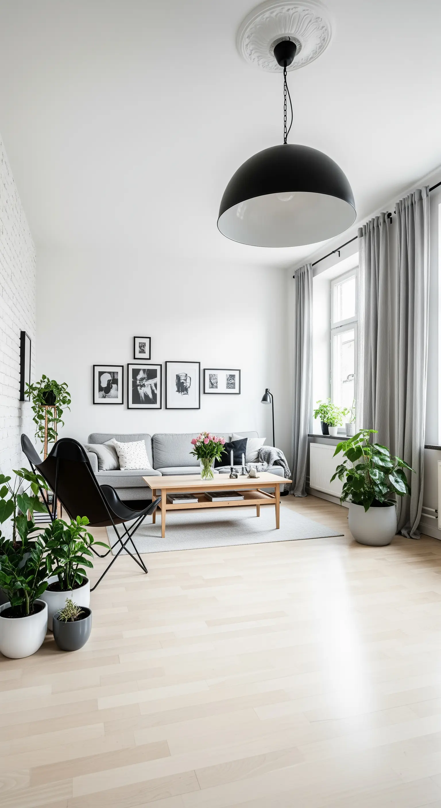 Salotto luminoso in stile scandinavo-industriale con lampada a cupola nera e tante piante.