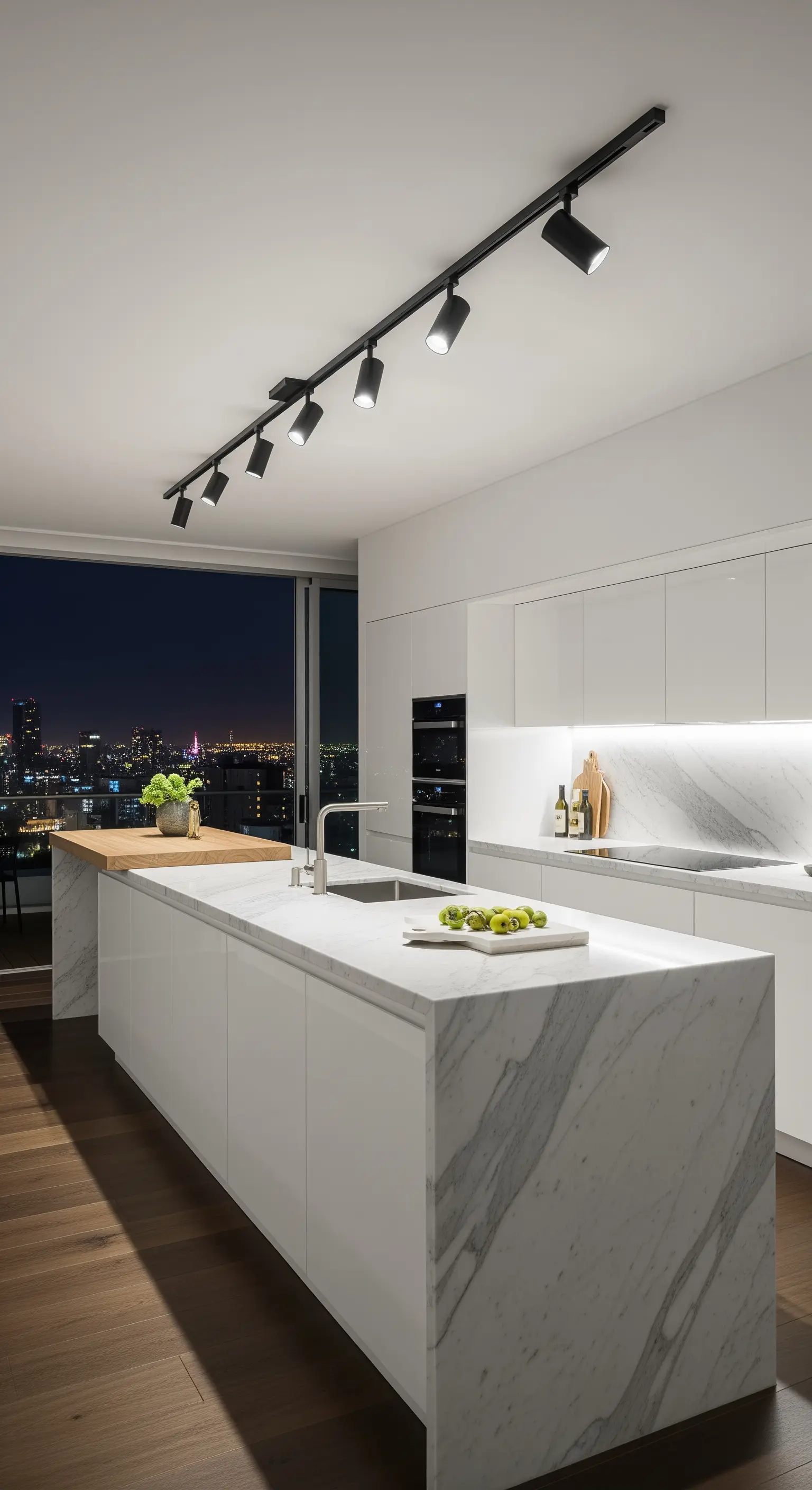 Cucina bianca minimalista con isola in marmo e sistema di illuminazione a binario nero.