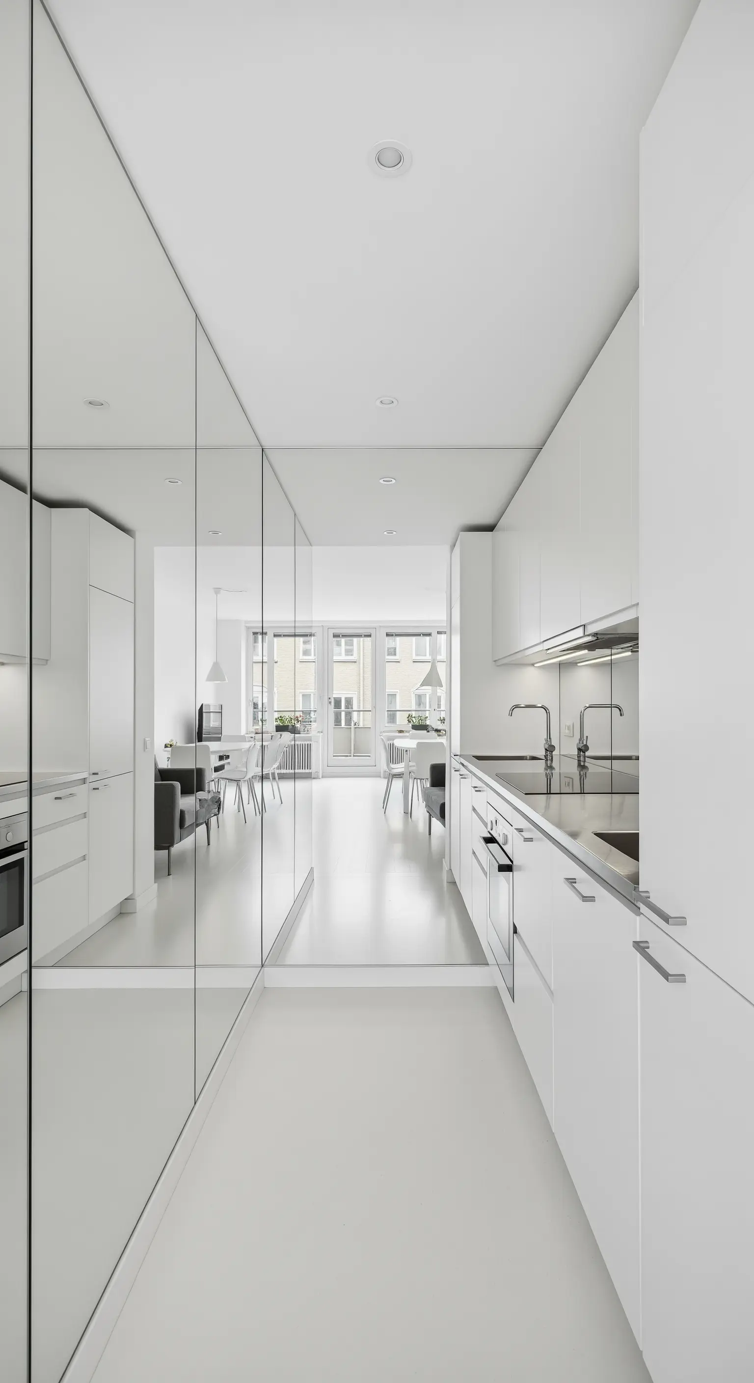 Cucina a corridoio total white con un'intera parete rivestita di specchi.
