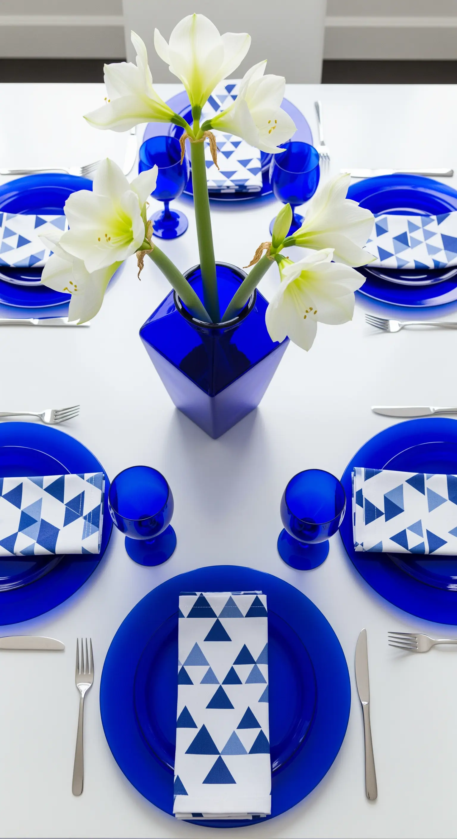 Tavola moderna con piatti blu cobalto e tovaglioli con motivo a triangoli.