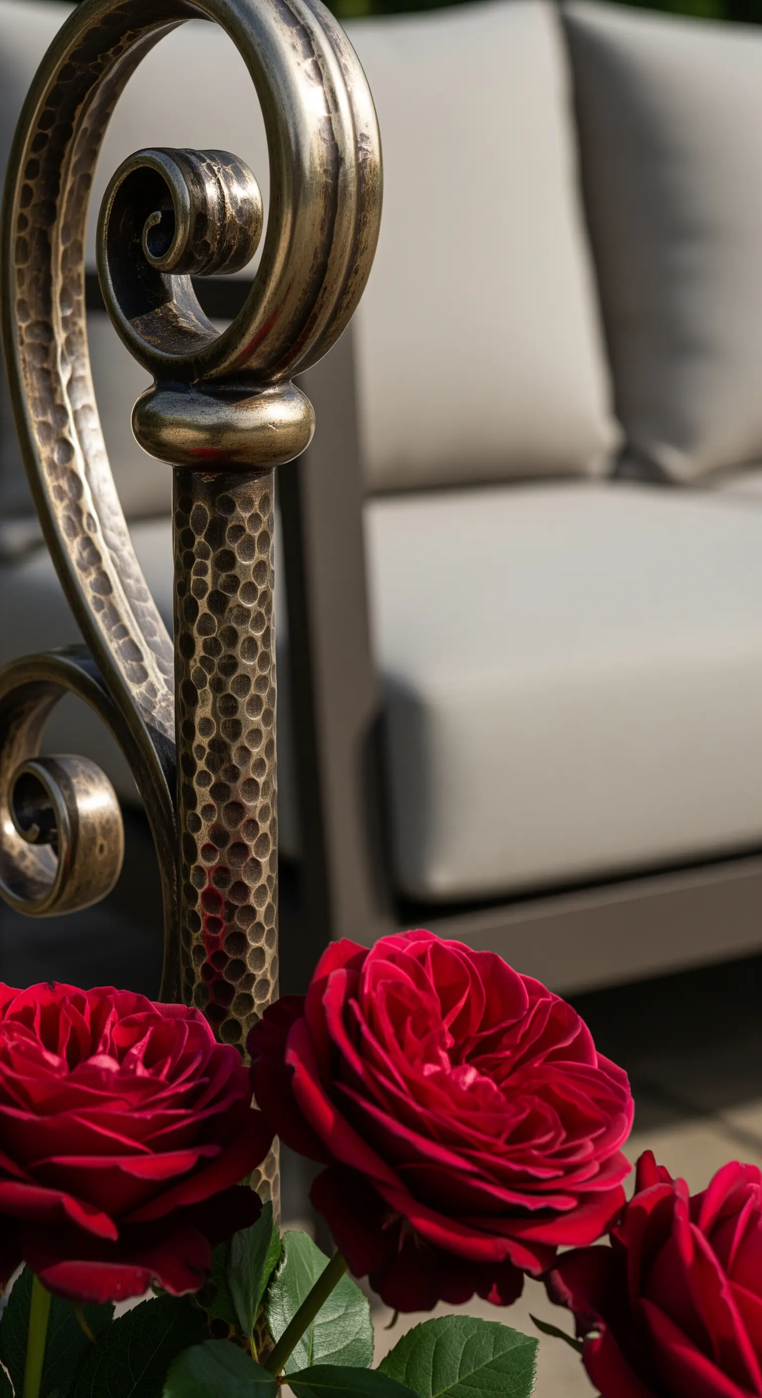 Dettaglio di un arredo in ferro battuto con finitura bronzea martellata e rose rosse.