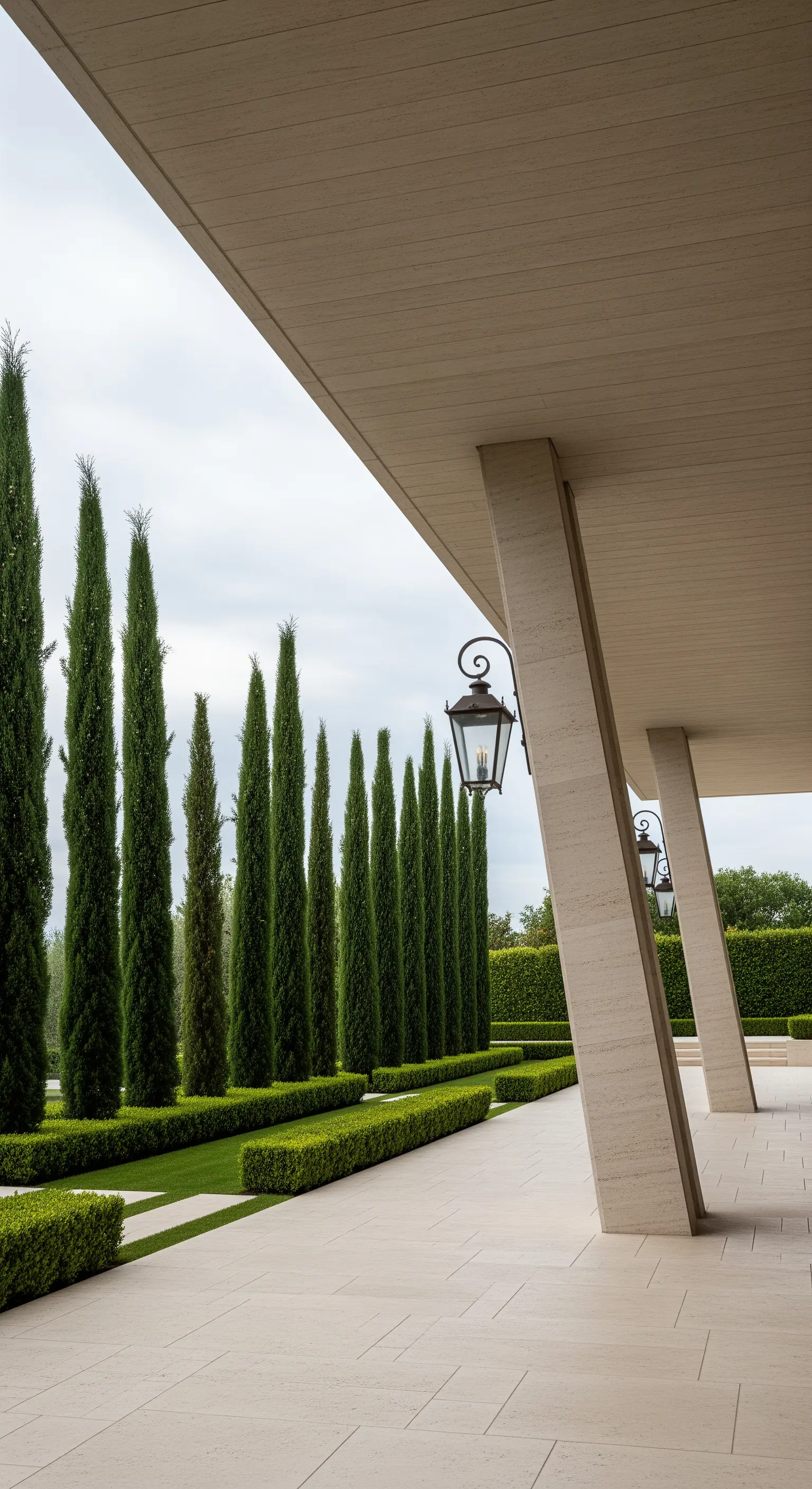 Portico moderno con colonne inclinate e una fila di alti cipressi che ne accentuano la verticalità
