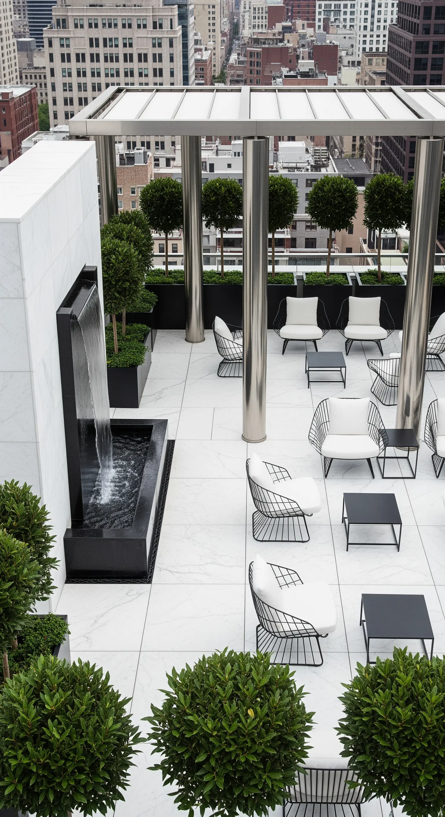 Terrazza panoramica con pavimento in marmo bianco, sedie in metallo nero e una fontana a cascata