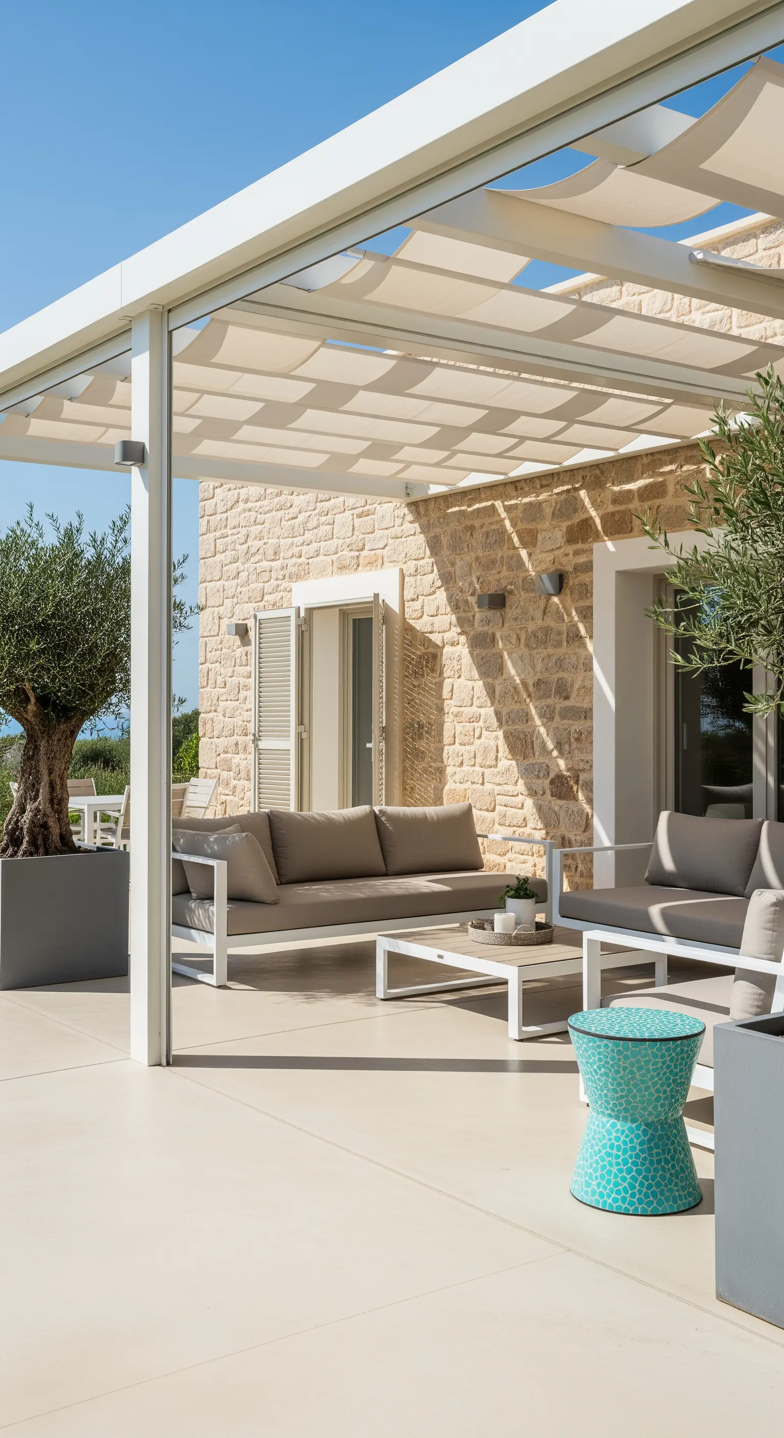 Veranda moderna con pergola bianca, divani grigi e uno sgabello turchese.