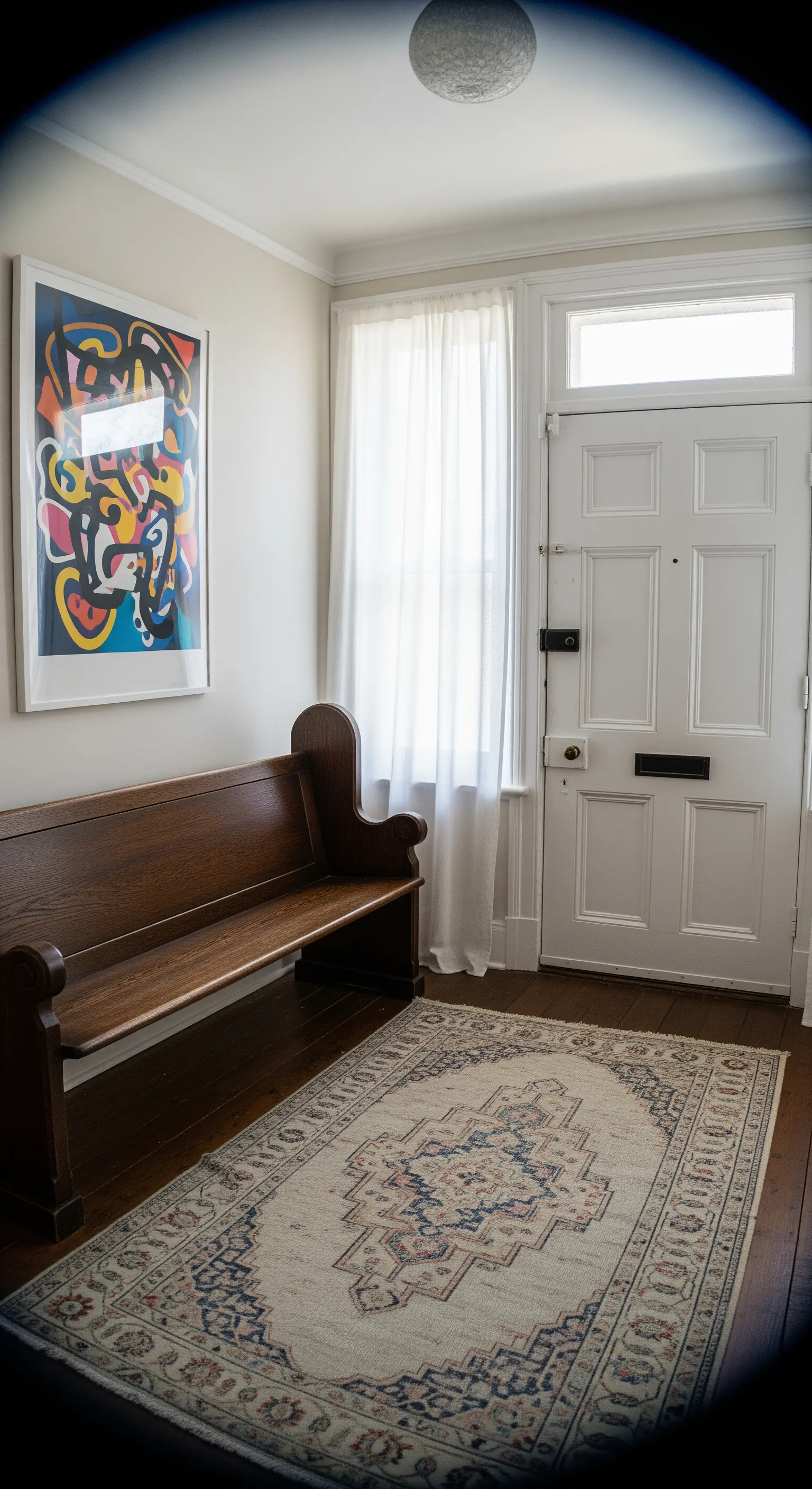 Ingresso eclettico con panca da chiesa in legno, quadro astratto colorato e tappeto kilim.