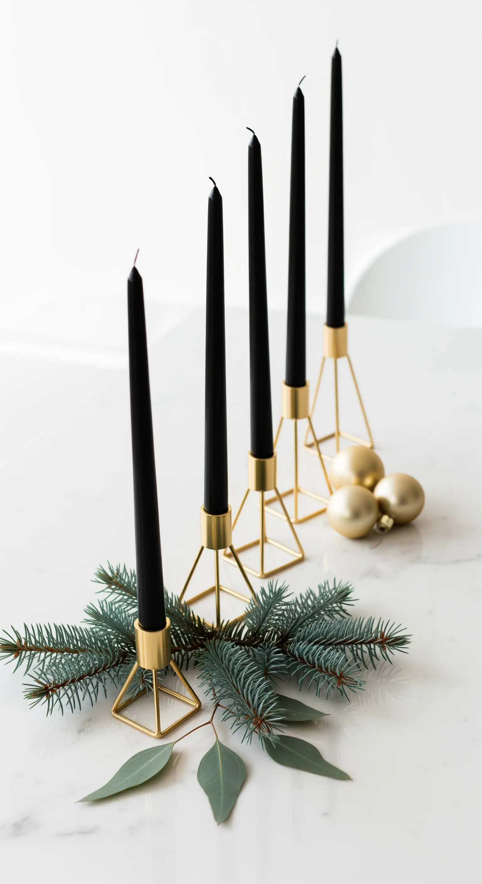 Centrotavola minimalista con candele nere in portacandele geometrici dorati su marmo.