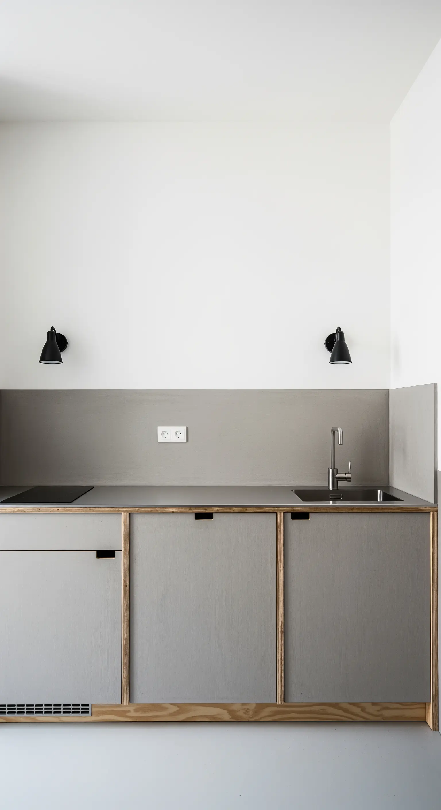 Cucina minimalista in laminato grigio con bordi in compensato a vista.