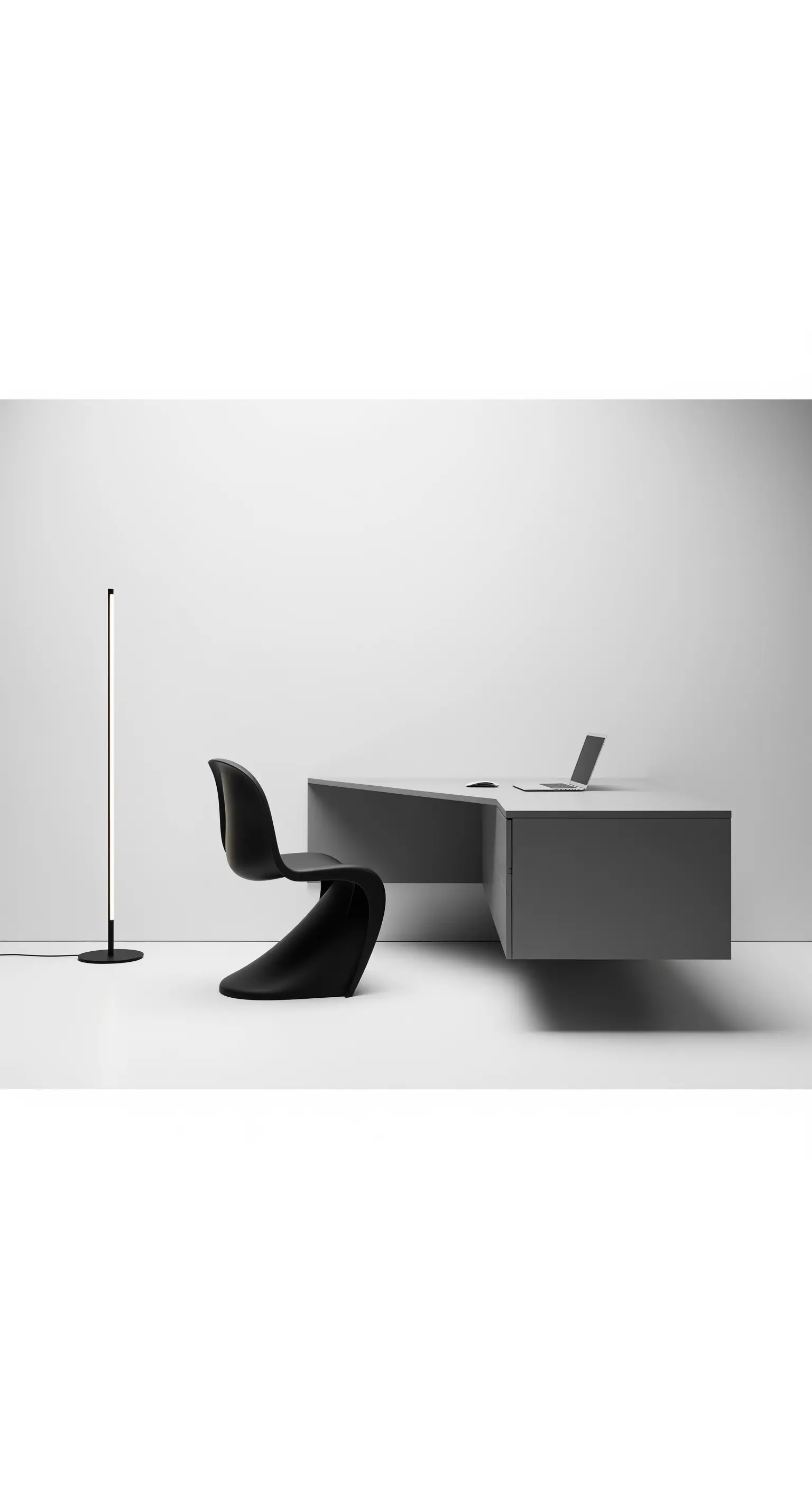 Scrivania grigia sospesa, sedia nera scultorea e lampada da terra minimalista.