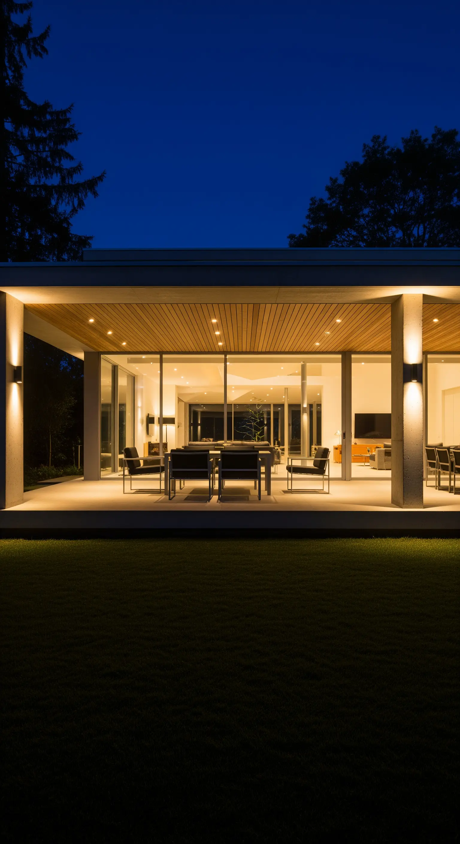 Veranda moderna illuminata di notte con faretti a soffitto, applique a parete e luci a terra