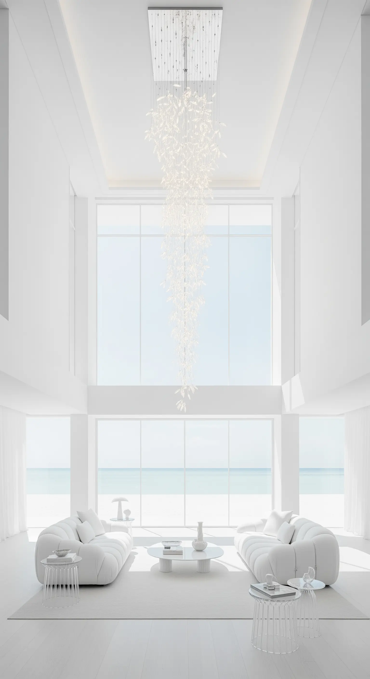 Soggiorno minimalista total white con un lungo lampadario a cascata di cristalli e vista mare.