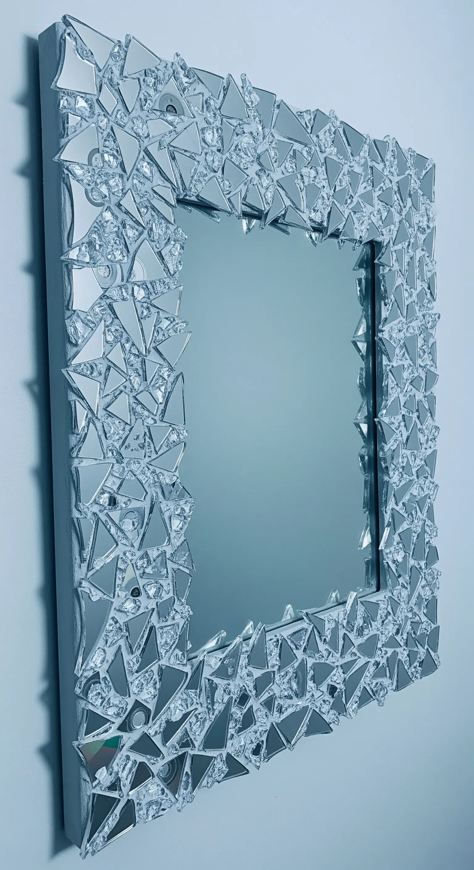 Specchio quadrato con una cornice tridimensionale fatta di frammenti di specchio e CD sovrapposti.