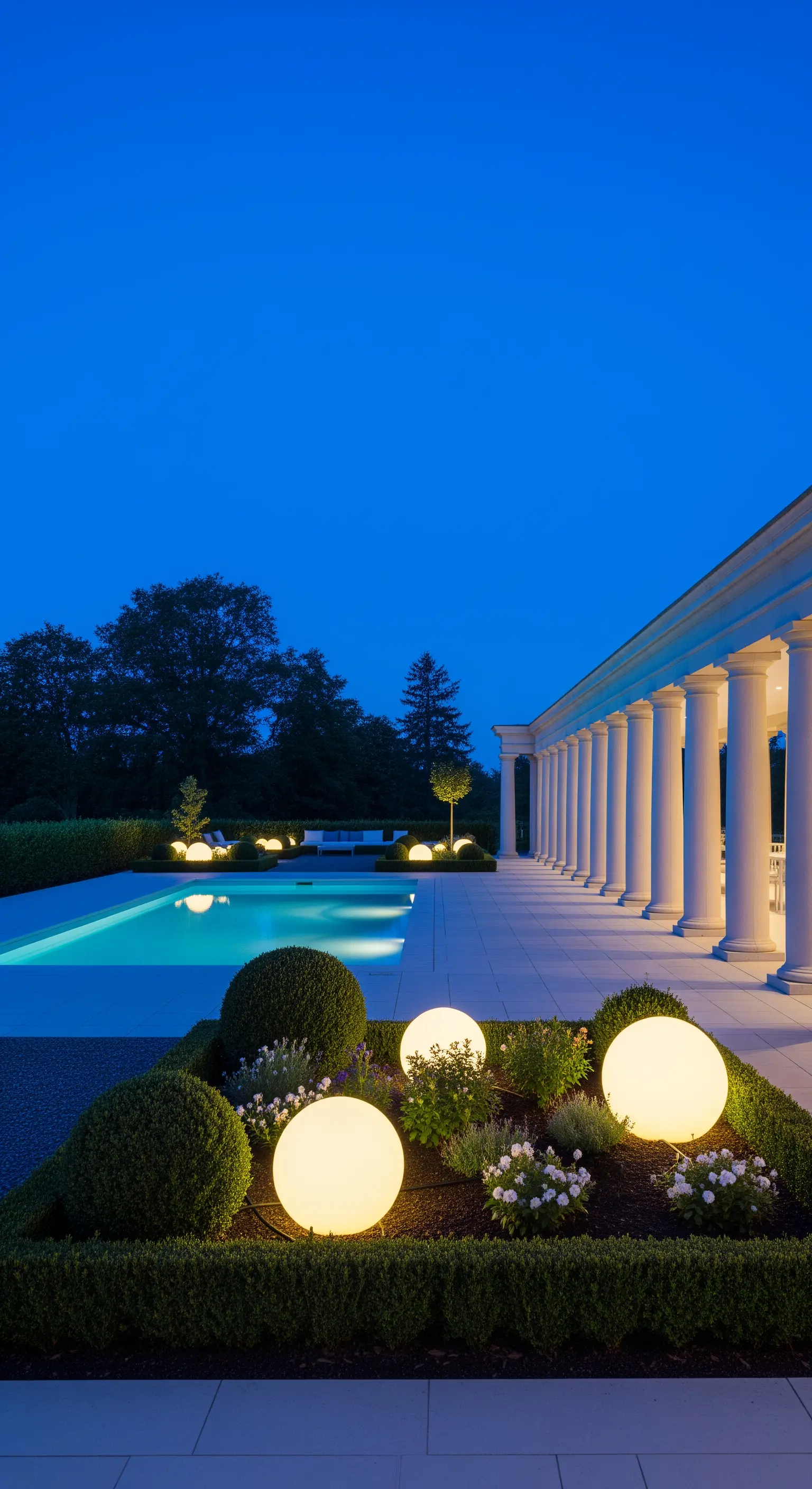 Giardino formale di notte con piscina e colonne, illuminato da grandi sfere luminose decorative