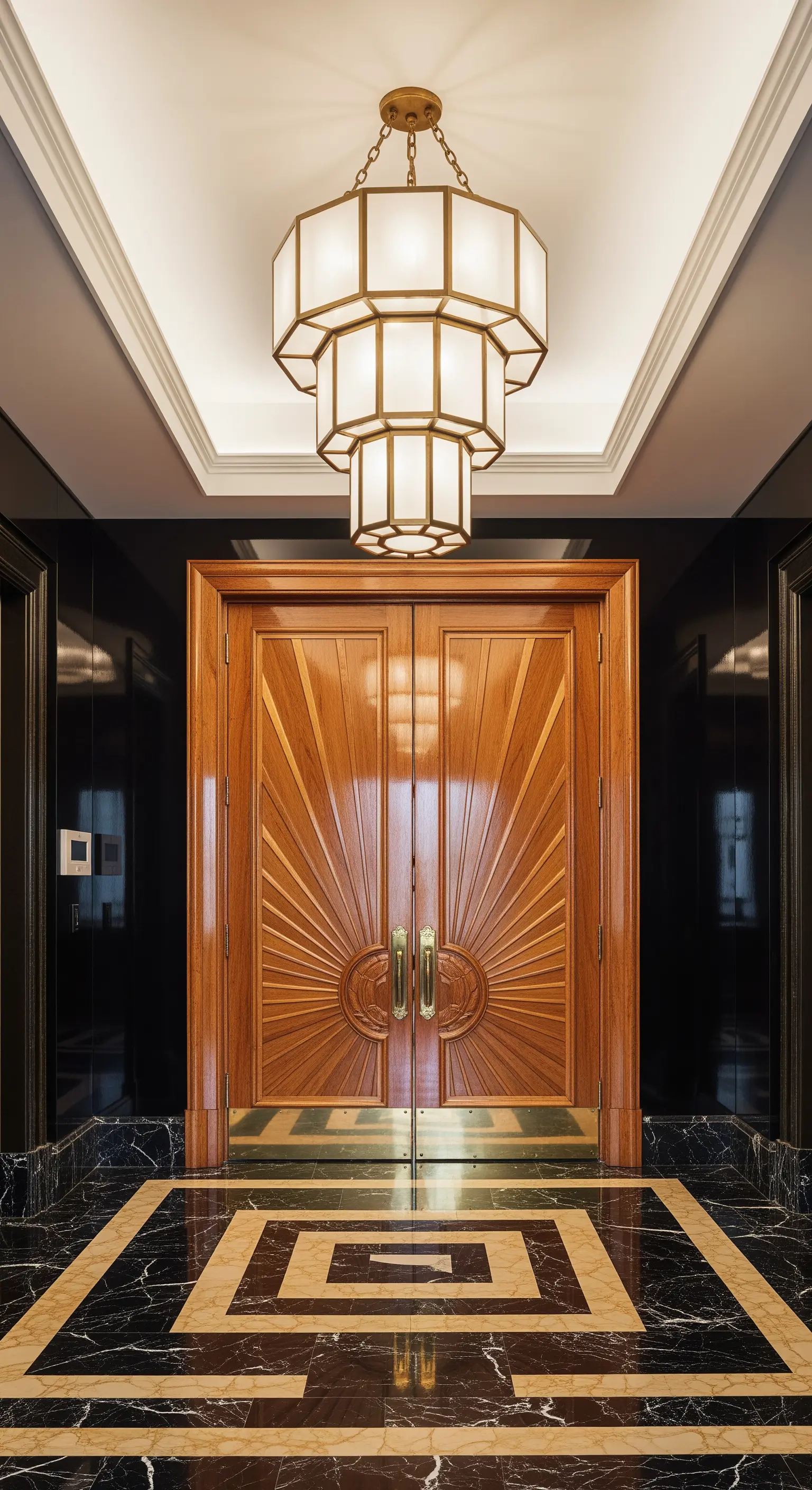 Ingresso Art Déco con porta a raggiera, pavimento in marmo nero e oro e un grande lampadario a gradoni.